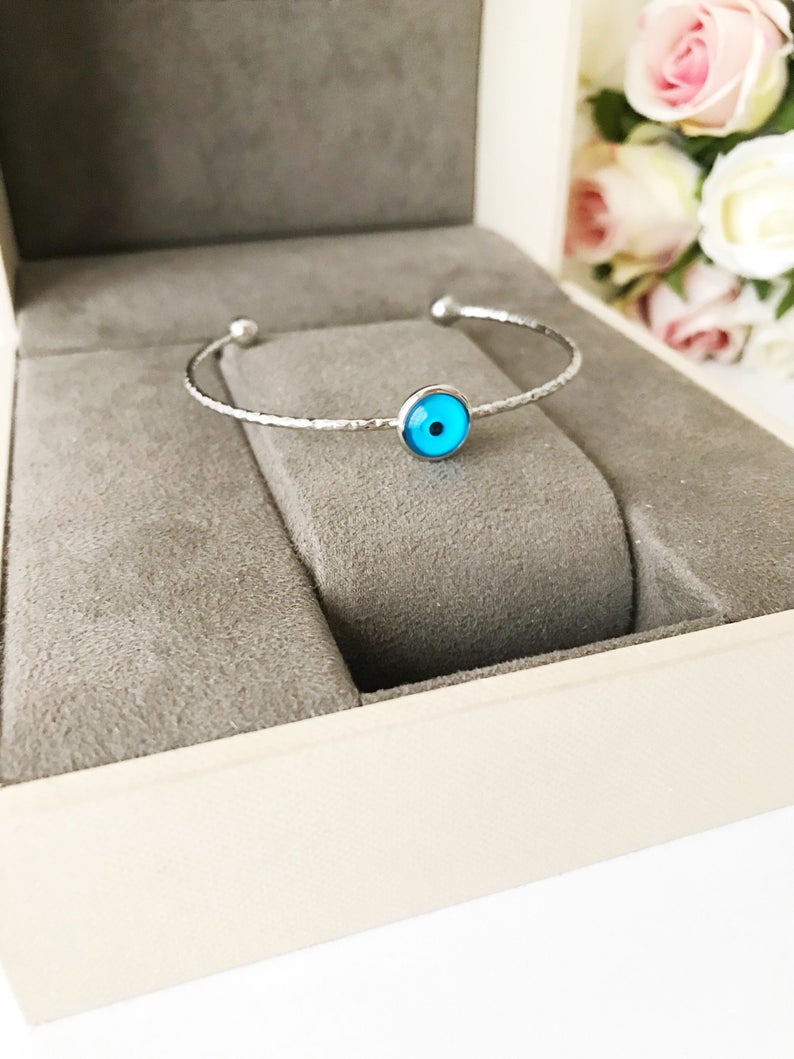 A delicate silver evil eye bracelet featuring a movable oval charm, crafted from tarnish-resistant stainless steel.