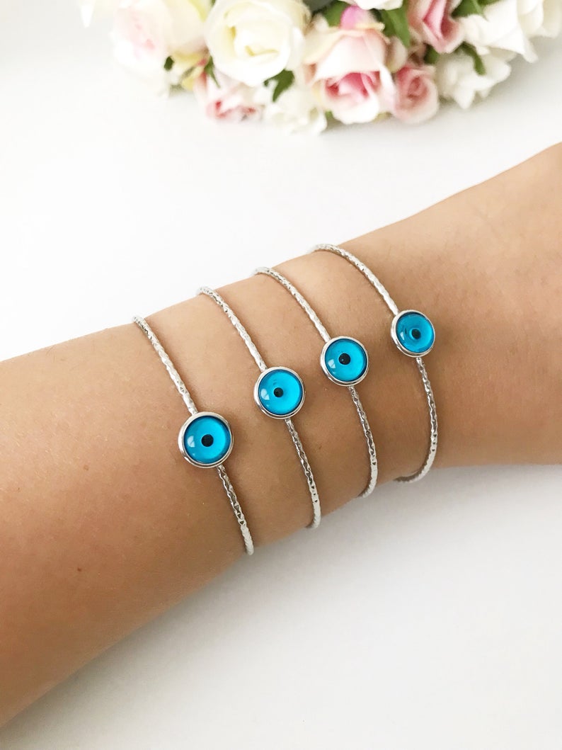 A delicate silver evil eye bracelet featuring a movable oval charm, crafted from tarnish-resistant stainless steel.