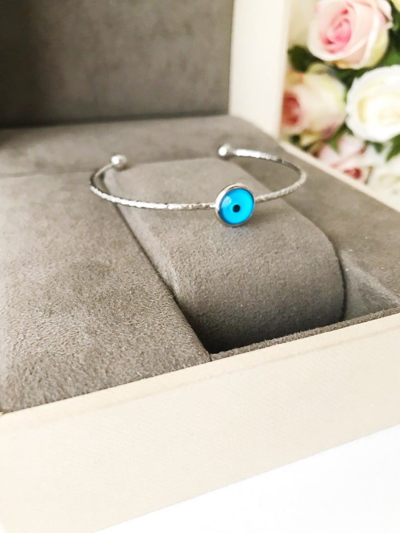 A delicate silver evil eye bracelet featuring a movable oval charm, crafted from tarnish-resistant stainless steel.