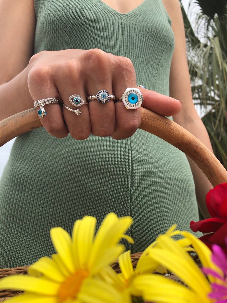 A stylish silver adjustable ring featuring a blue evil eye bead and zircon accents, symbolizing protection and good luck.