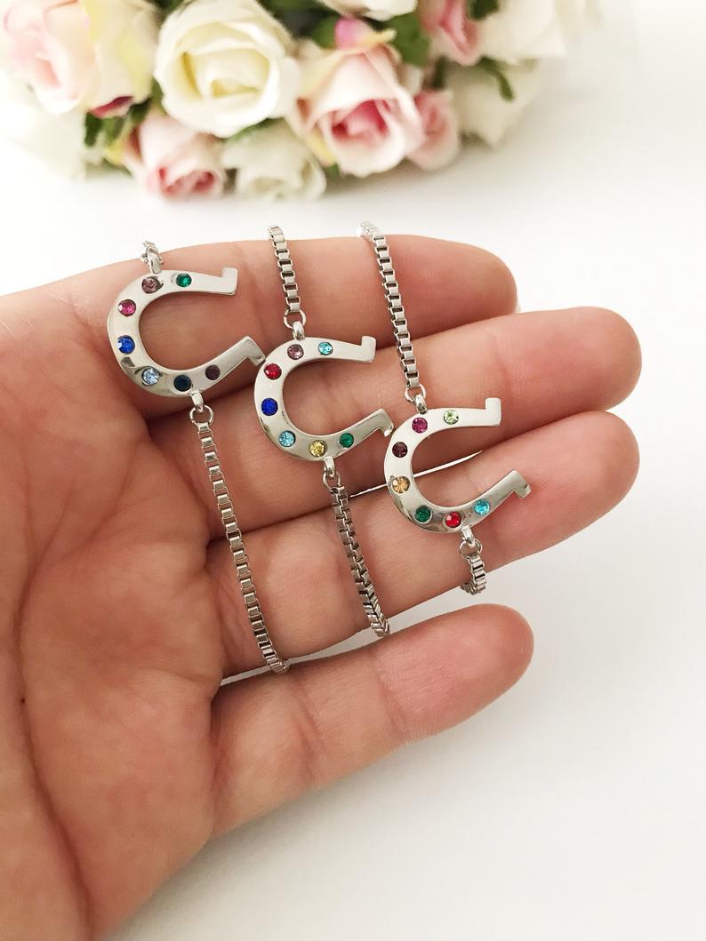 A beautiful silver horseshoe bracelet featuring a zirconia charm, adjustable design, and tarnish-resistant stainless steel material.