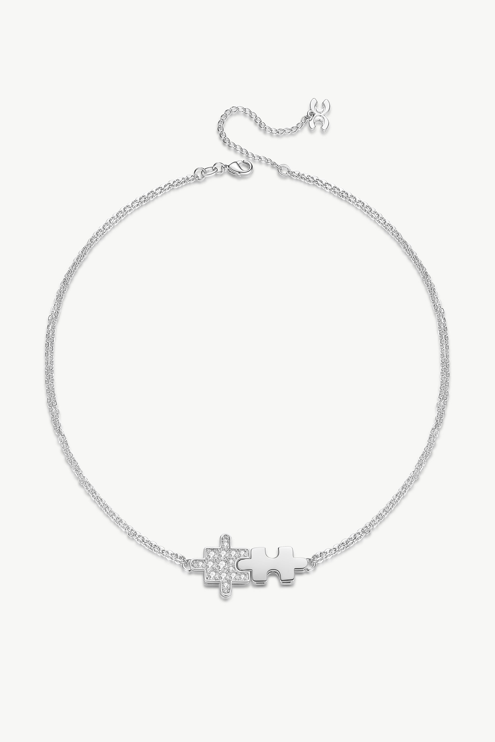 A beautiful Silver Jigsaw Puzzle Necklace featuring a jigsaw-shaped pendant adorned with sparkling cubic zirconia stones, showcasing its elegant design.