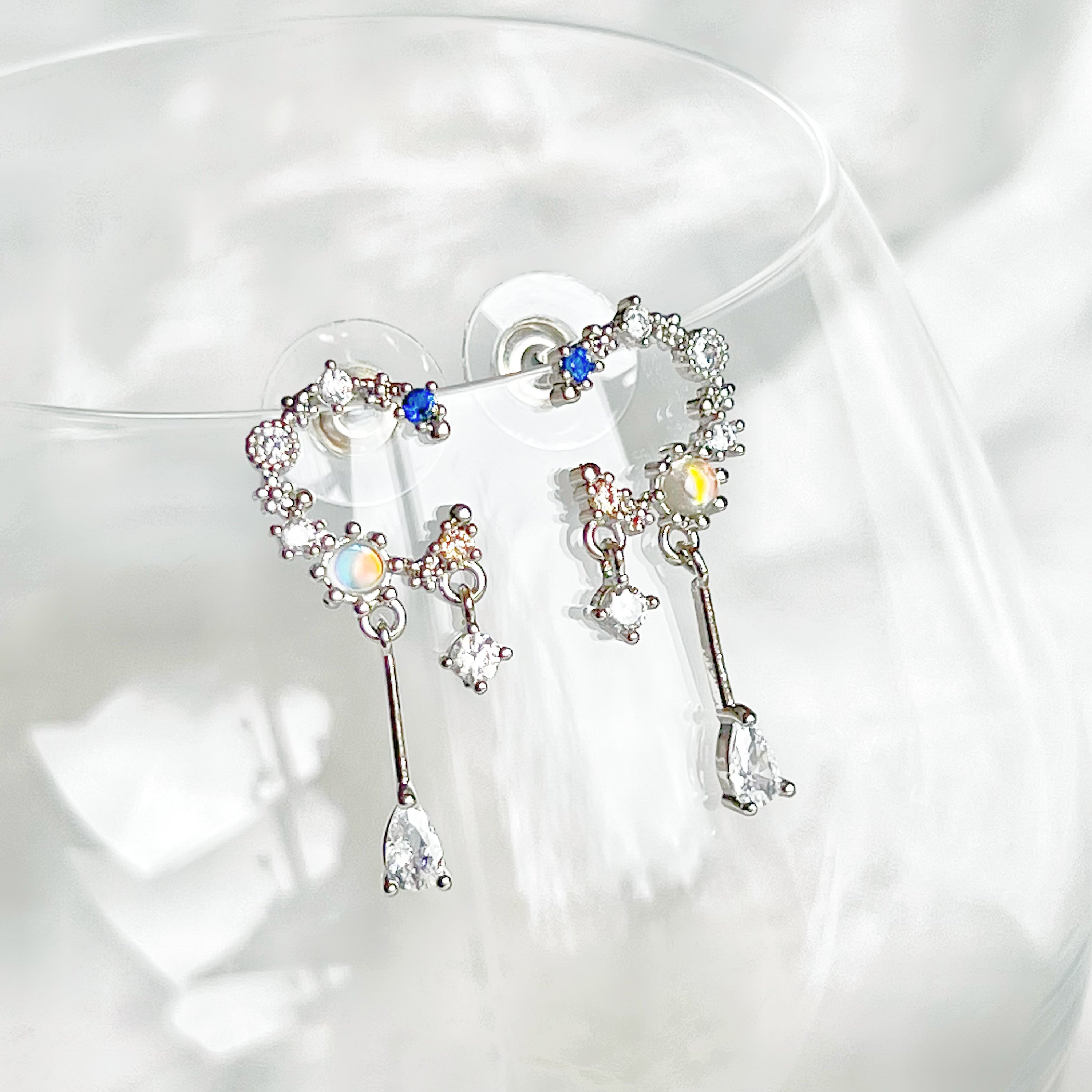 A pair of Silver Moon Drop Earrings featuring intricate star and moon designs, crafted from sterling silver and gold-plated bronze.