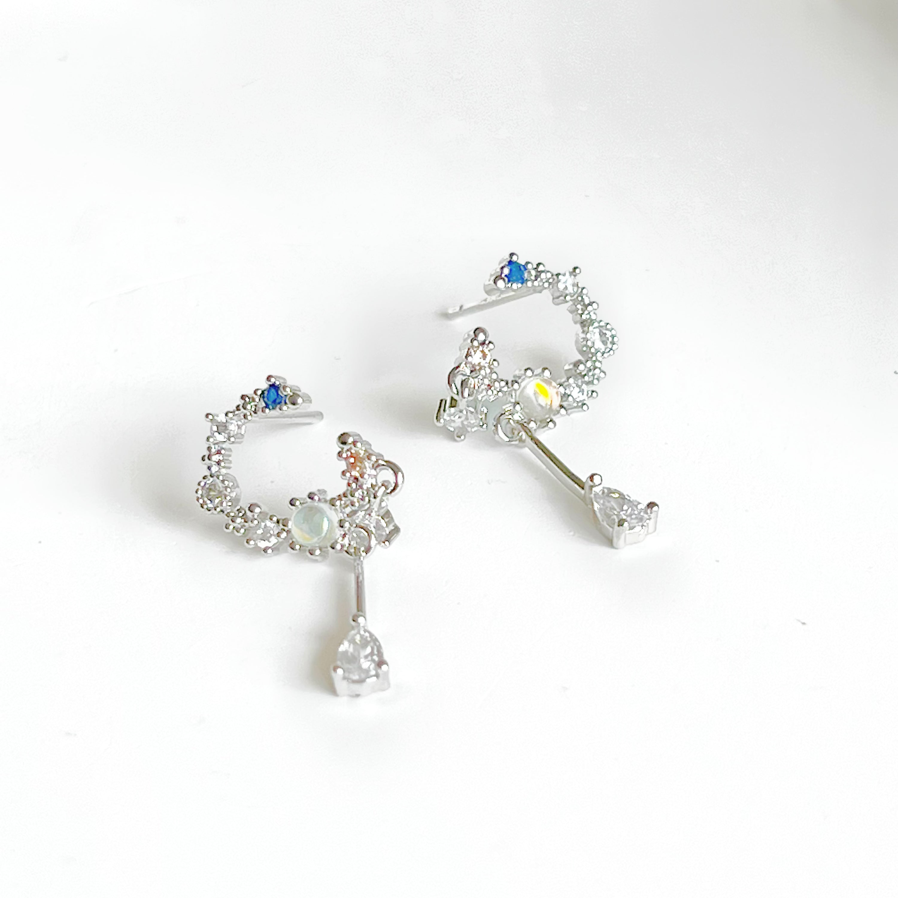 A pair of Silver Moon Drop Earrings featuring intricate star and moon designs, crafted from sterling silver and gold-plated bronze.