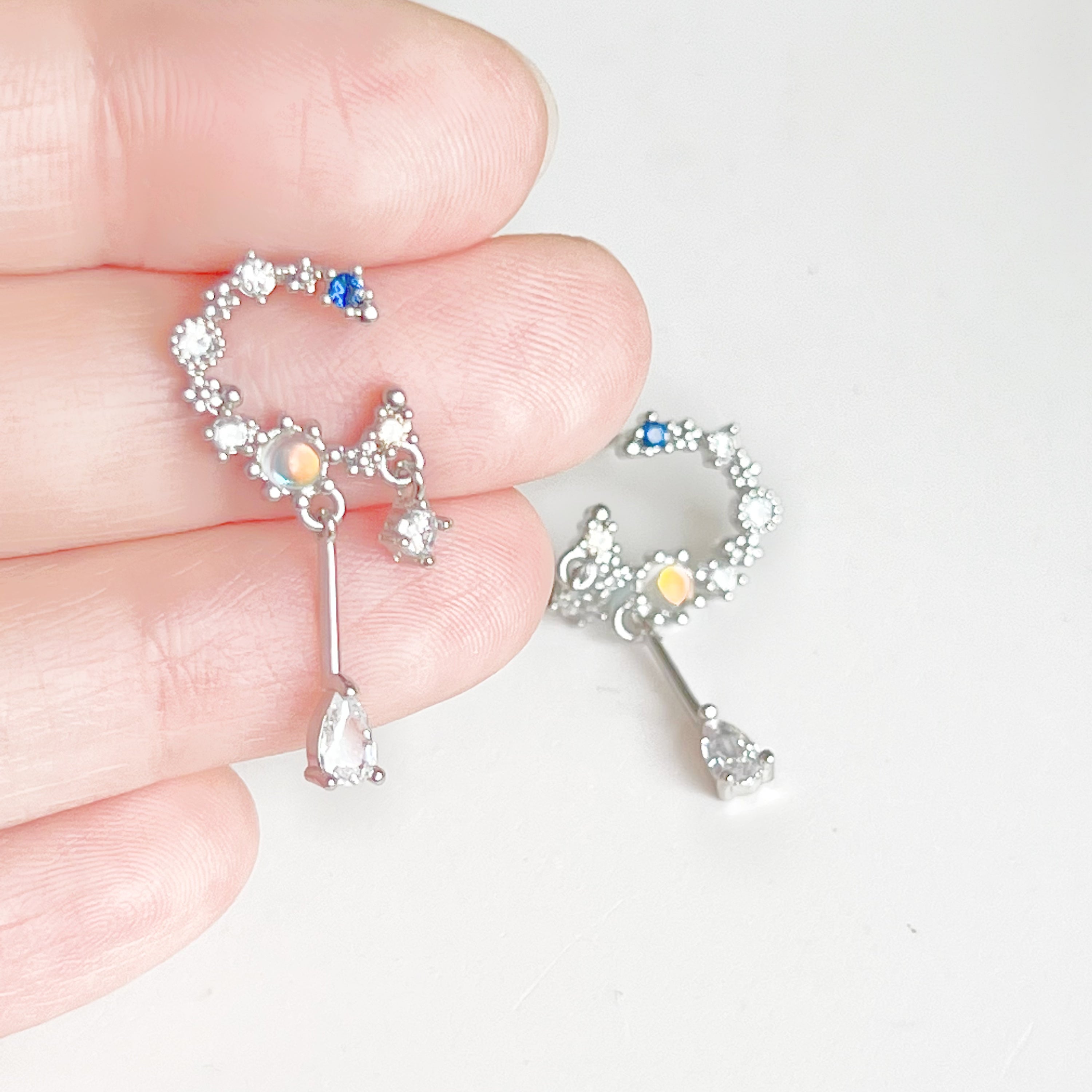 A pair of Silver Moon Drop Earrings featuring intricate star and moon designs, crafted from sterling silver and gold-plated bronze.