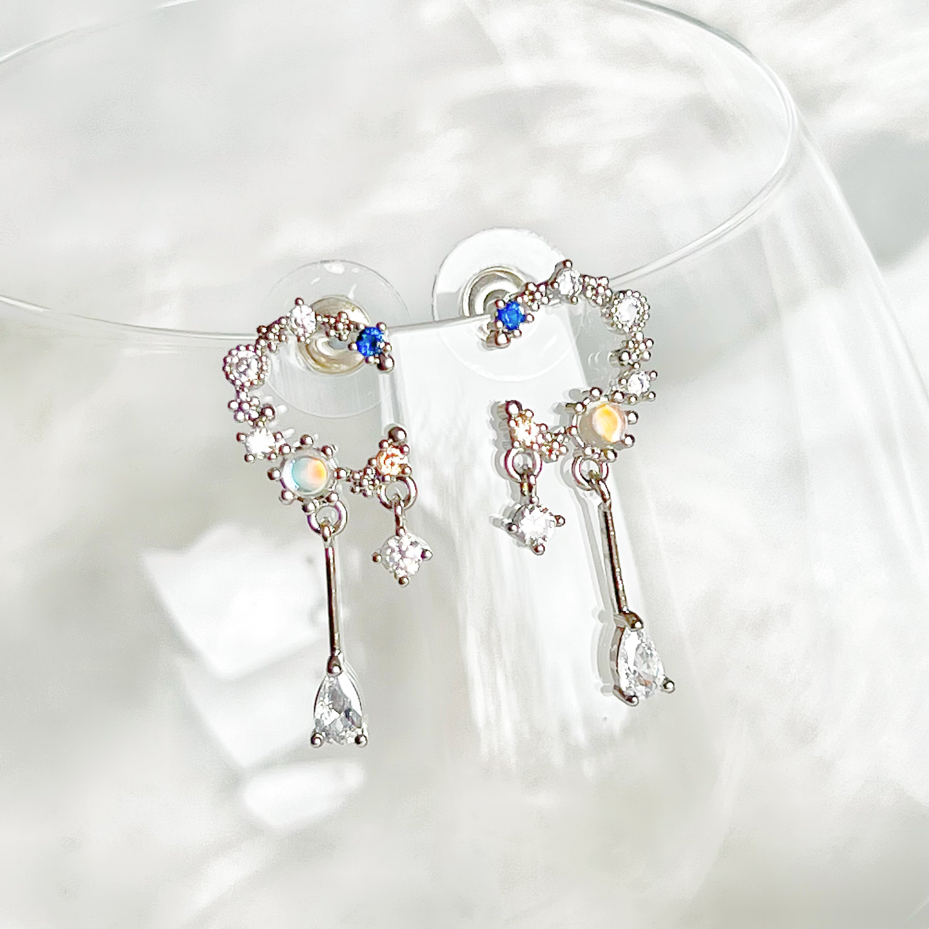 A pair of Silver Moon Drop Earrings featuring intricate star and moon designs, crafted from sterling silver and gold-plated bronze.