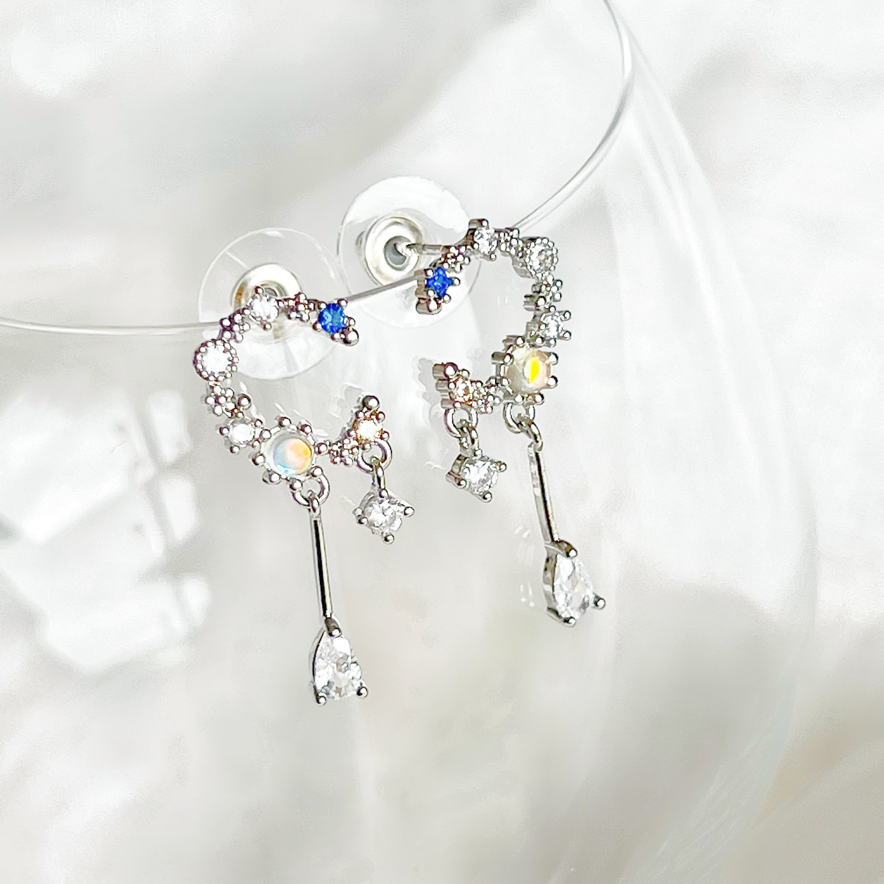 A pair of Silver Moon Drop Earrings featuring intricate star and moon designs, crafted from sterling silver and gold-plated bronze.