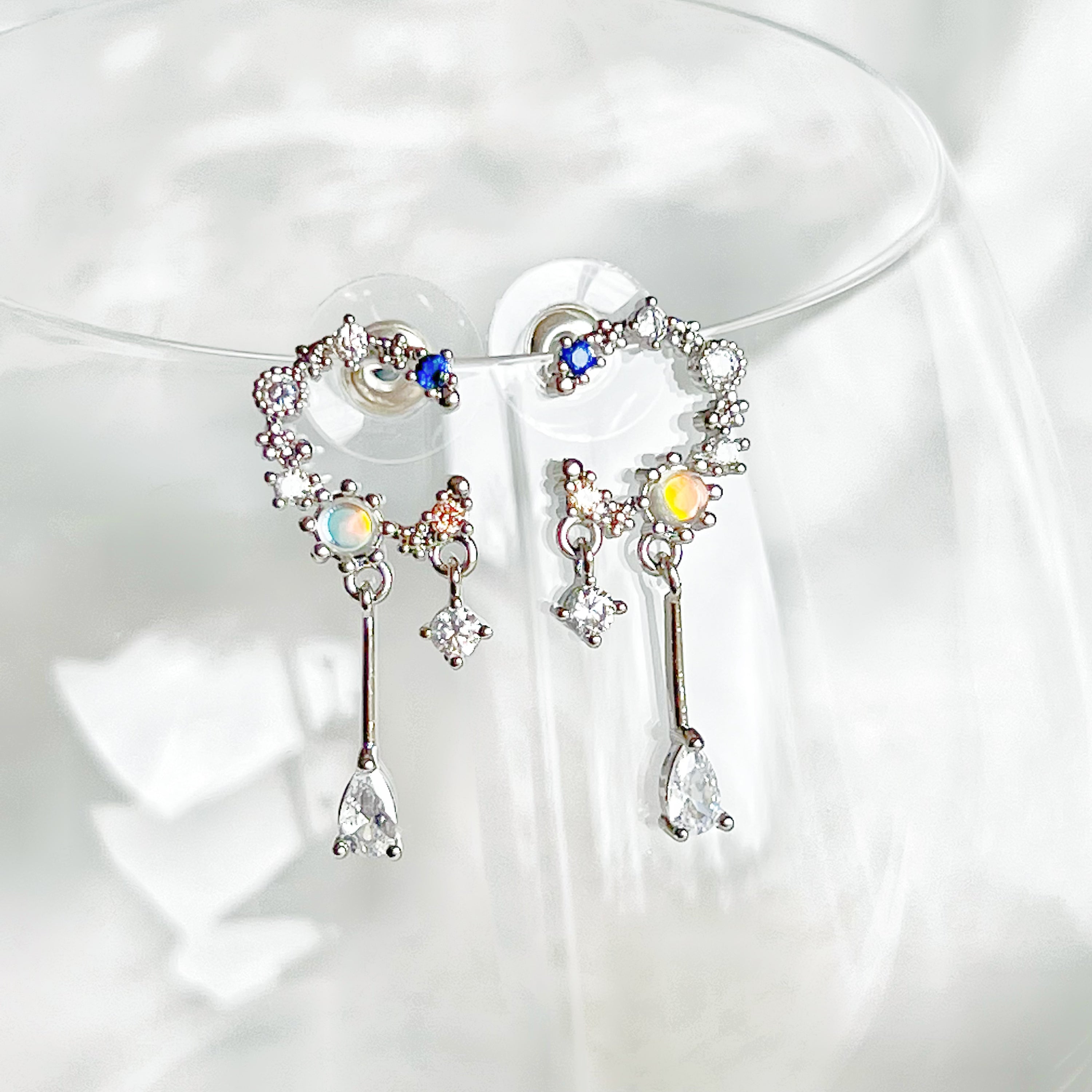 A pair of Silver Moon Drop Earrings featuring intricate star and moon designs, crafted from sterling silver and gold-plated bronze.