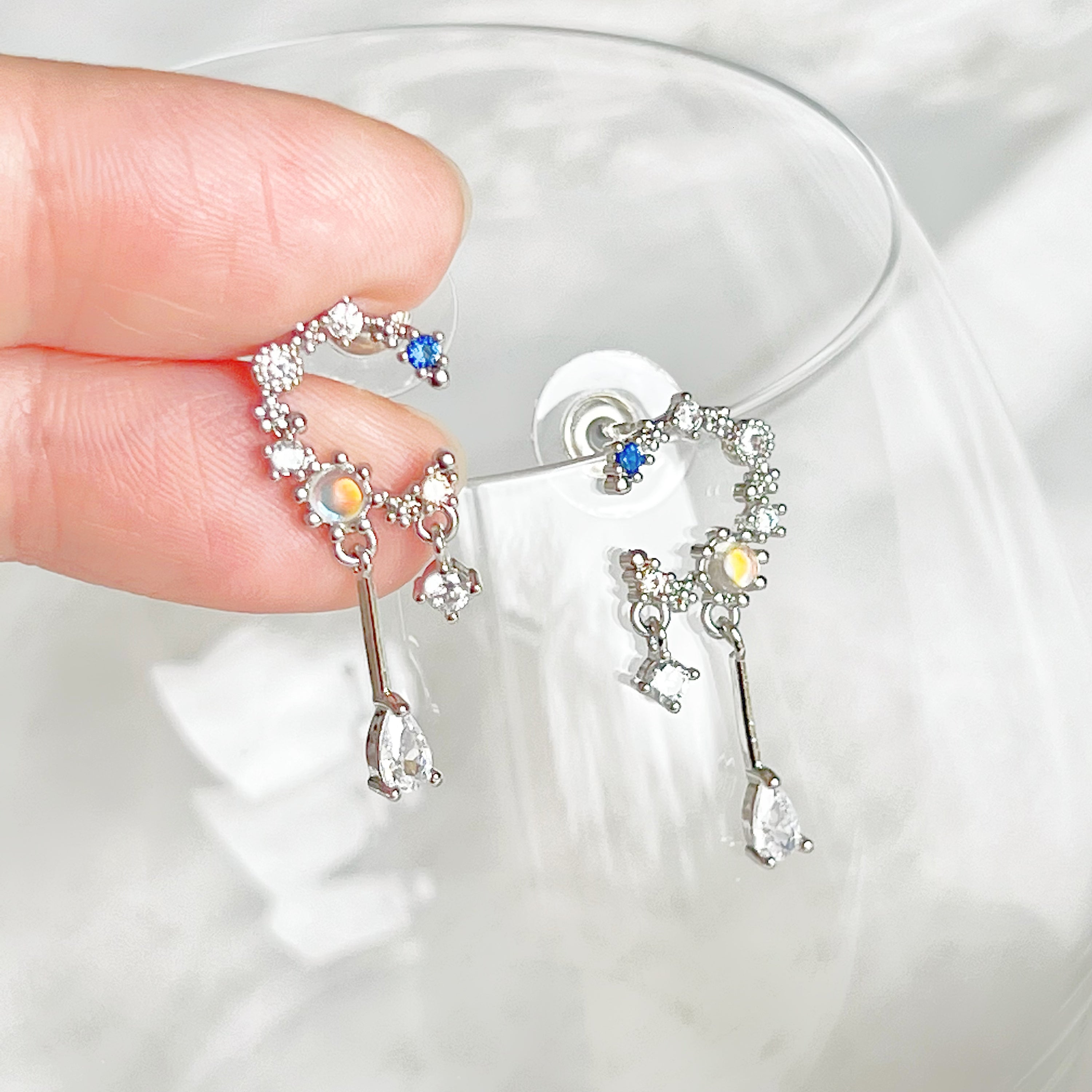 A pair of Silver Moon Drop Earrings featuring intricate star and moon designs, crafted from sterling silver and gold-plated bronze.