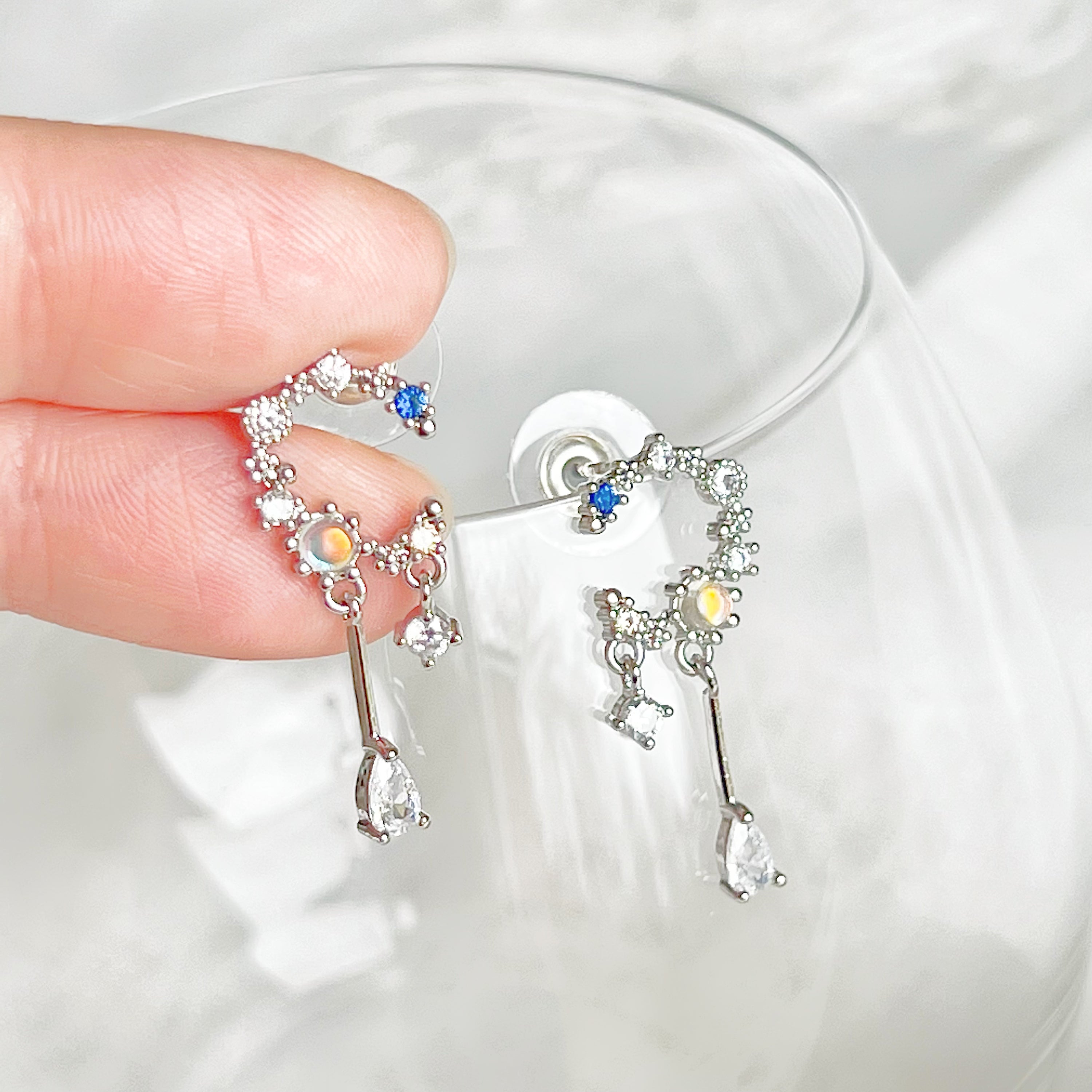 A pair of Silver Moon Drop Earrings featuring intricate star and moon designs, crafted from sterling silver and gold-plated bronze.