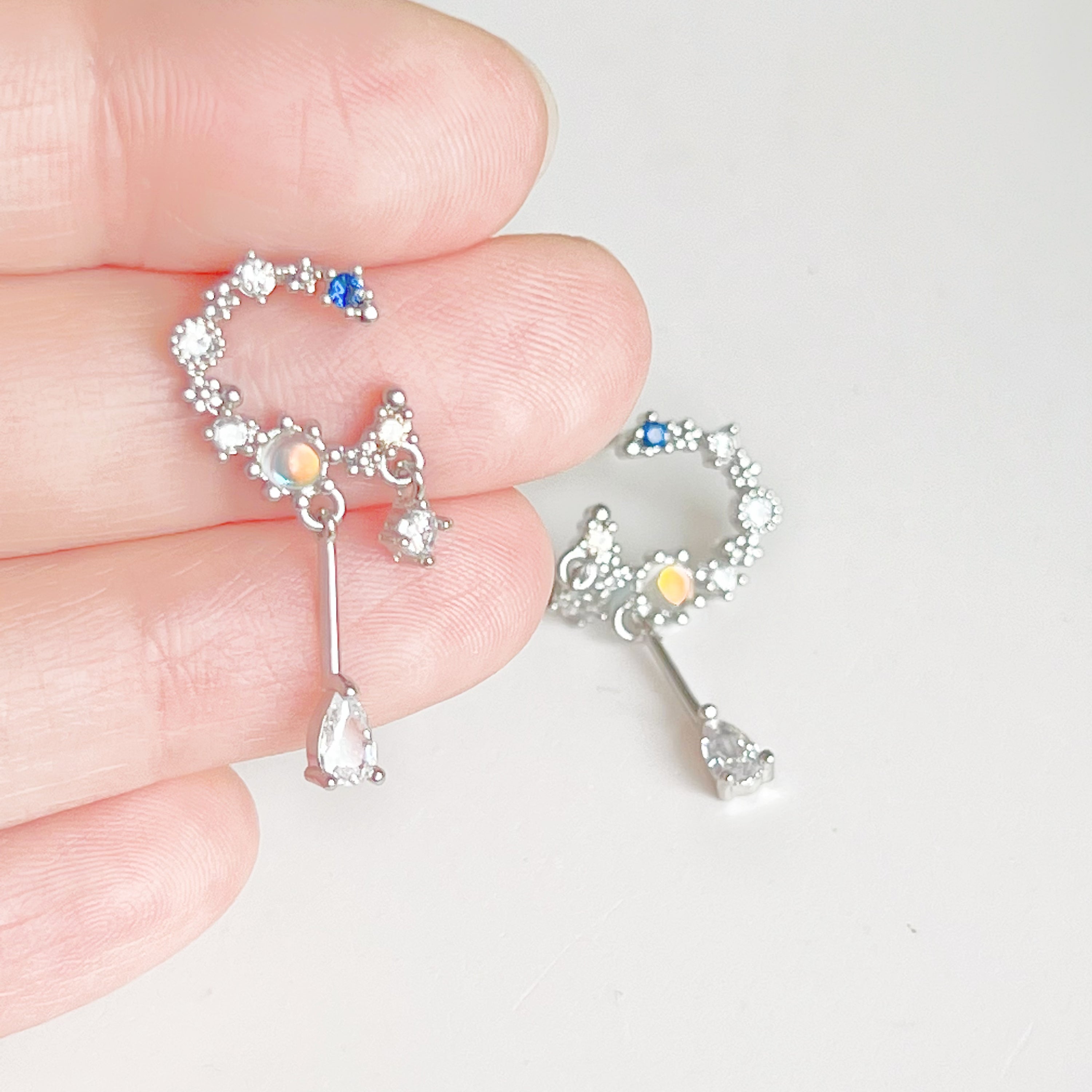 A pair of Silver Moon Drop Earrings featuring intricate star and moon designs, crafted from sterling silver and gold-plated bronze.