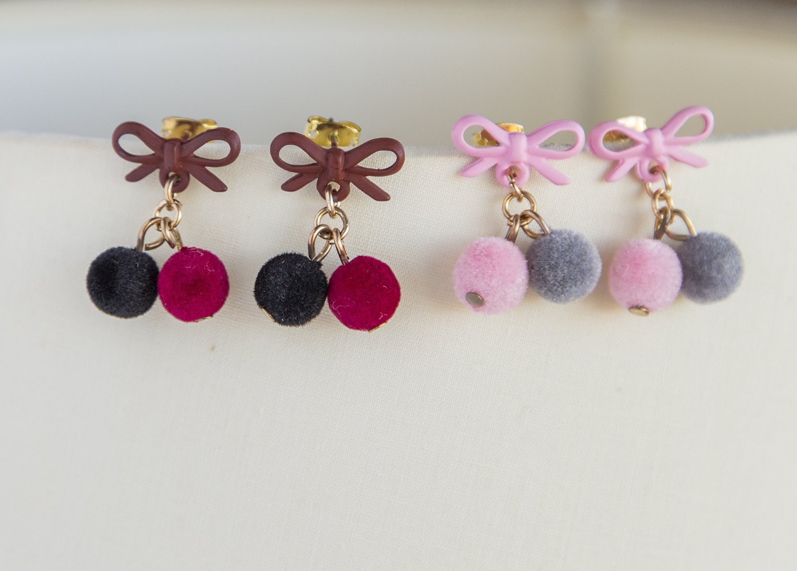 Small pompom earrings featuring pink, red, and black colors with gold plated studs and soft pompoms, elegantly designed for women.
