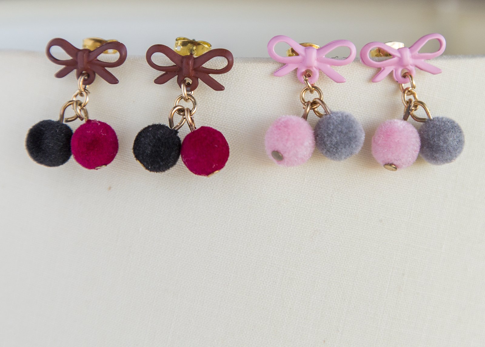 Small pompom earrings featuring pink, red, and black colors with gold plated studs and soft pompoms, elegantly designed for women.
