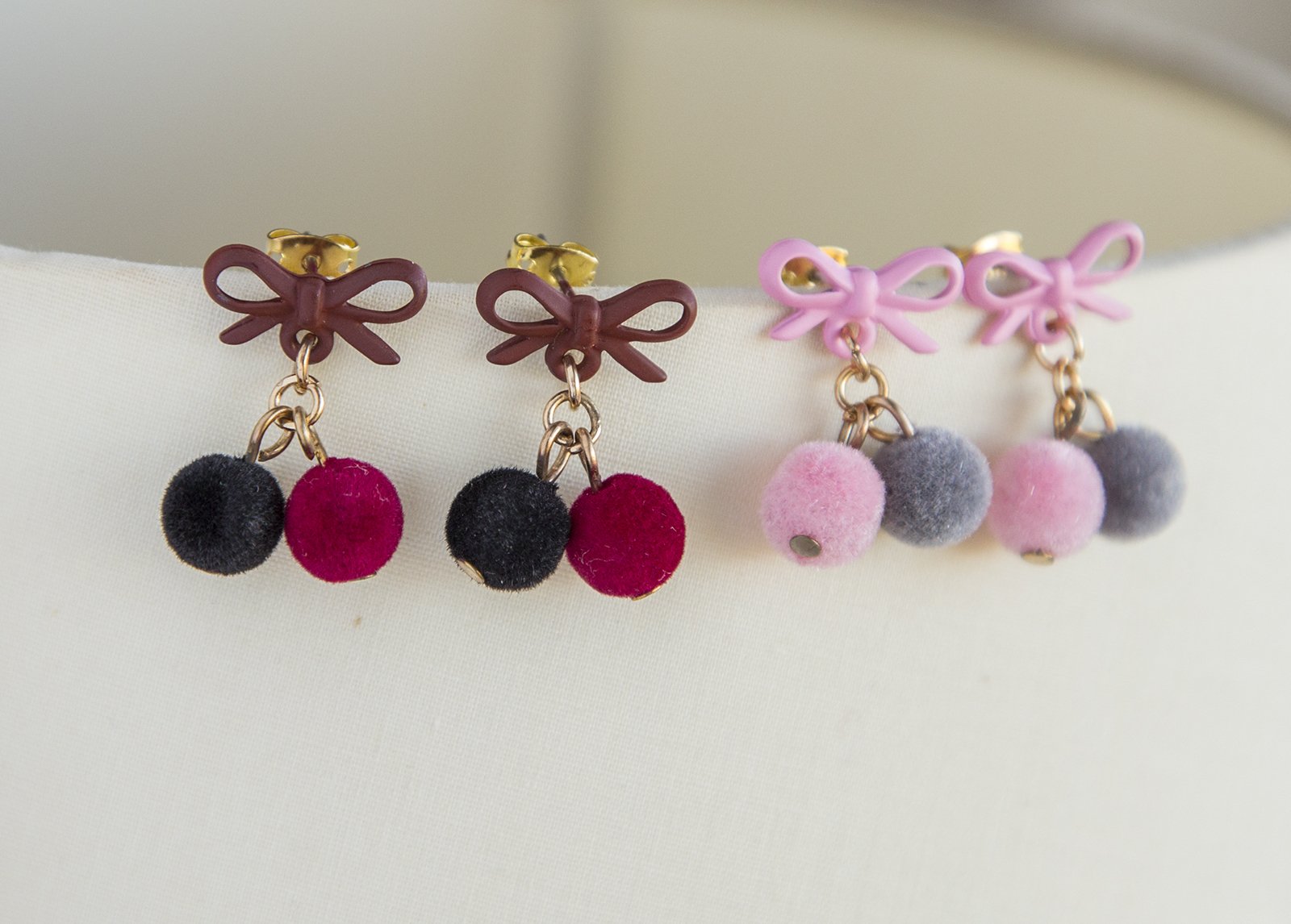 Small pompom earrings featuring pink, red, and black colors with gold plated studs and soft pompoms, elegantly designed for women.