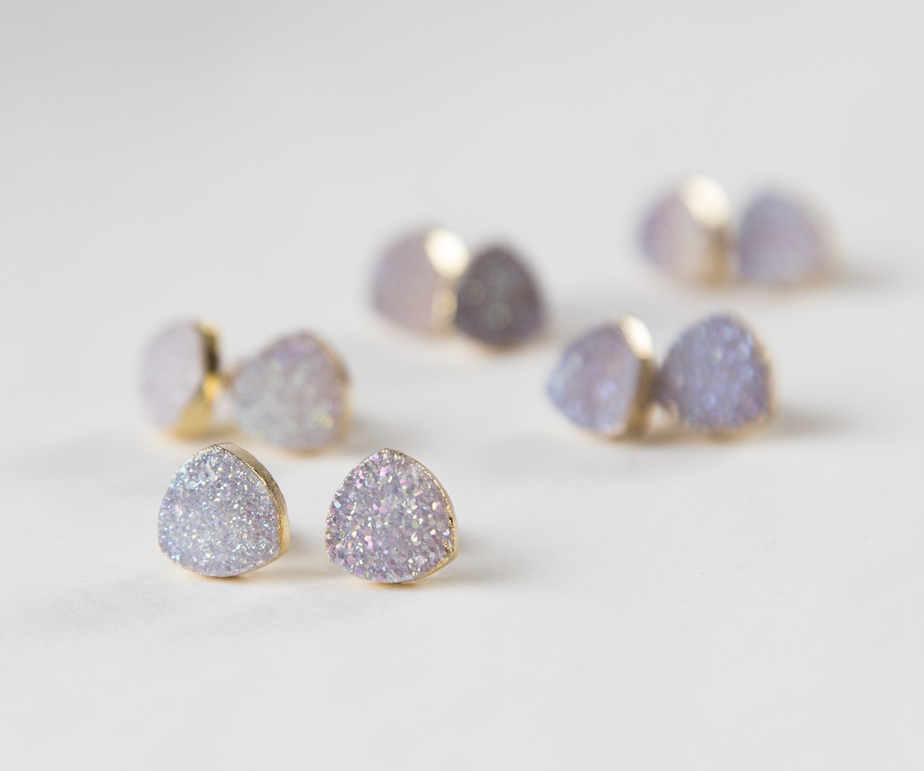 Small white druzy earrings with gold plated metal studs, showcasing their sparkly texture and elegant design.
