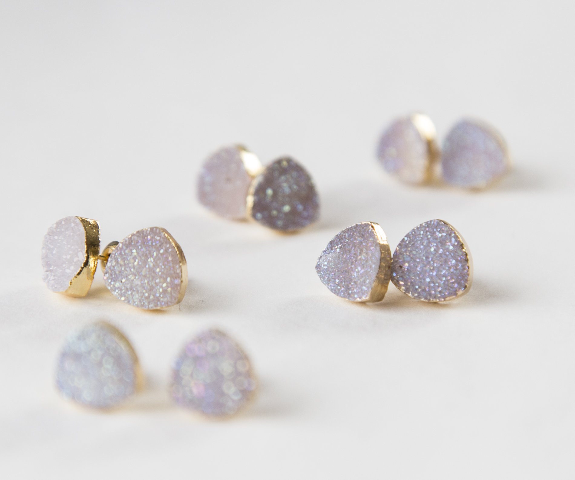 Small white druzy earrings with gold plated metal studs, showcasing their sparkly texture and elegant design.