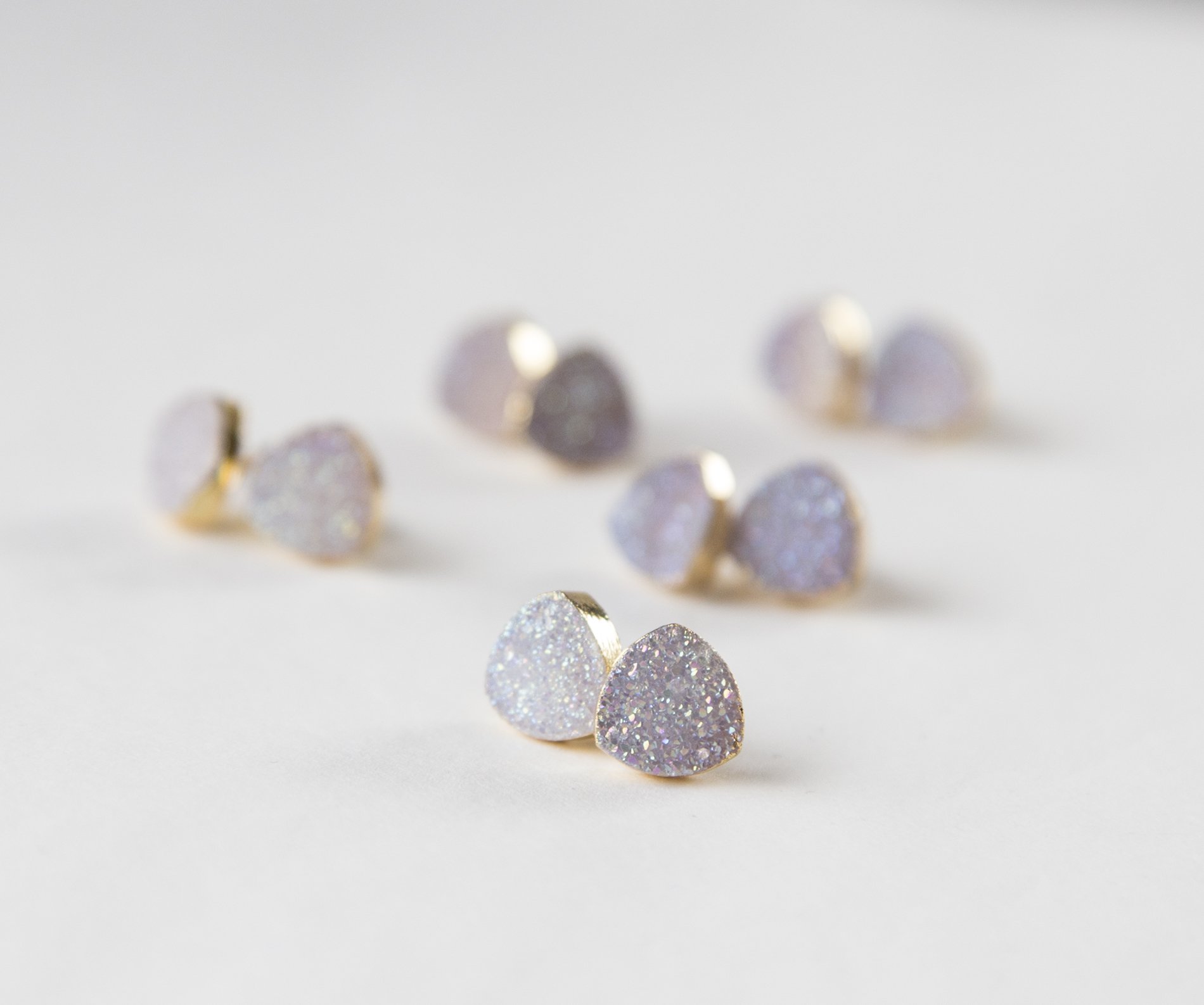 Small white druzy earrings with gold plated metal studs, showcasing their sparkly texture and elegant design.