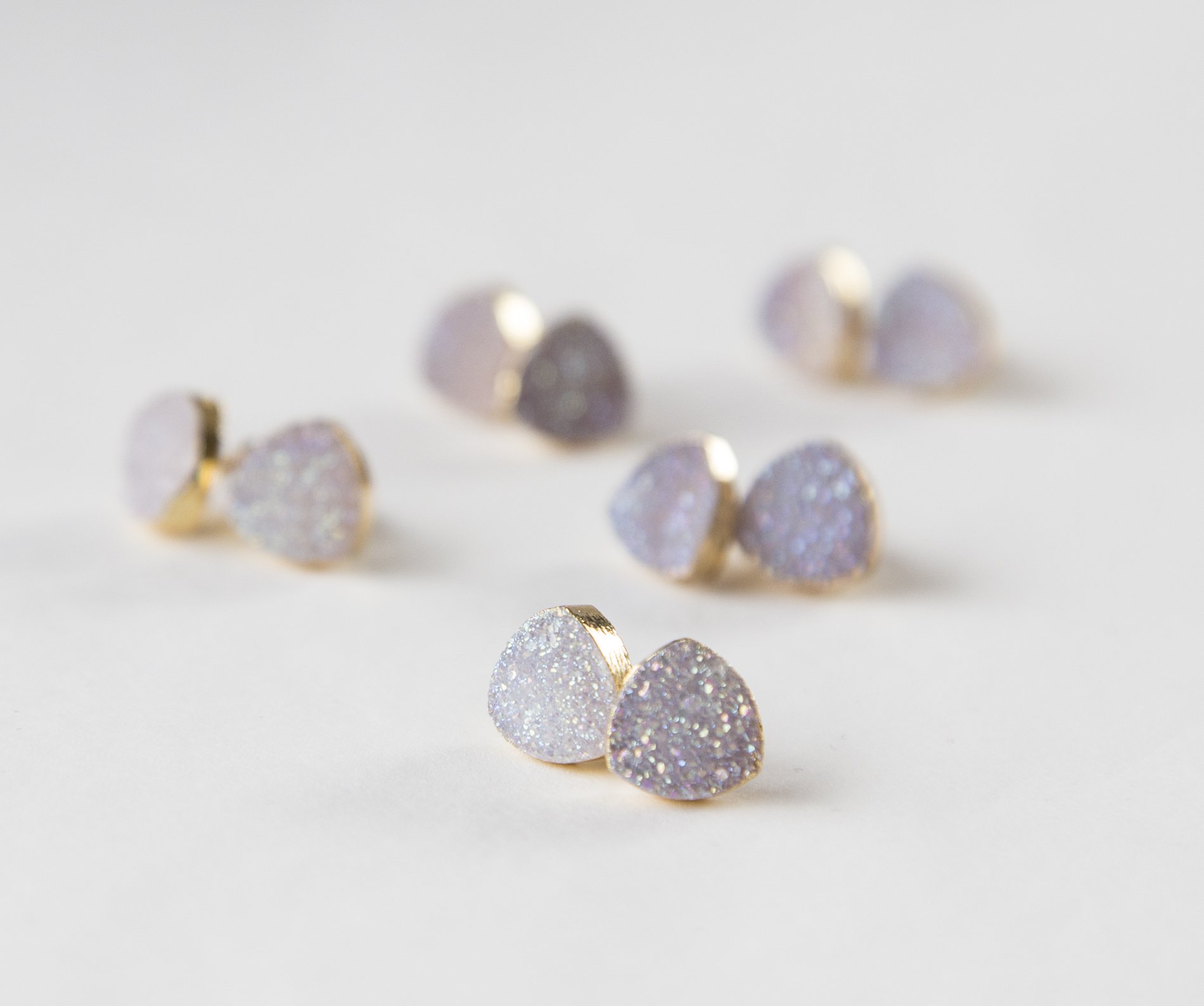 Small white druzy earrings with gold plated metal studs, showcasing their sparkly texture and elegant design.