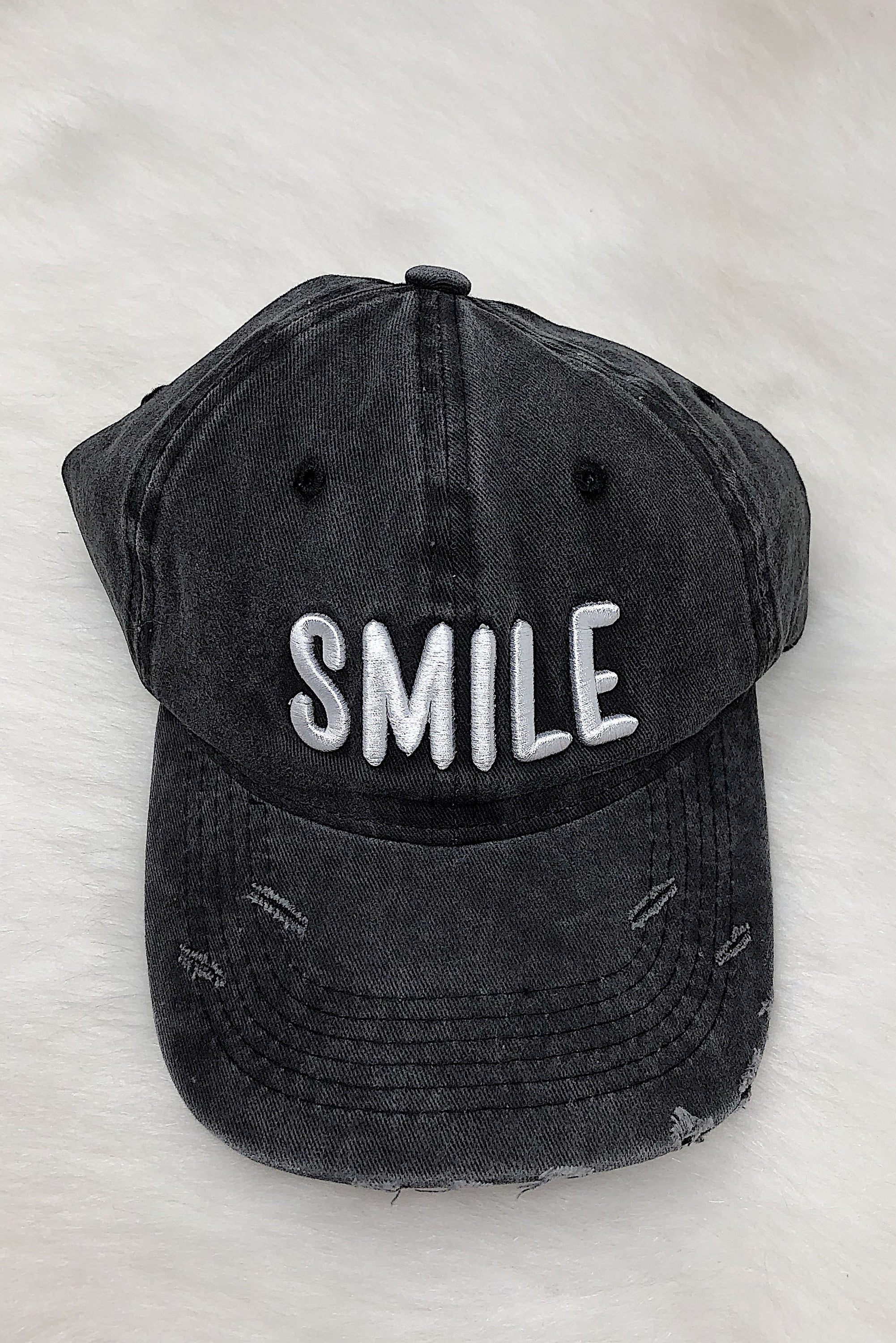 A stylish dark gray baseball cap with white 'SMILE' embroidery on the front, featuring a curved bill and adjustable strap at the back.