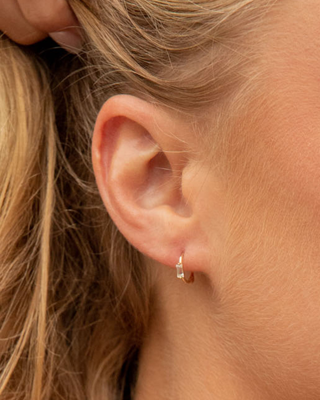 Elegant Solitaire Baguette White Sapphire Huggies featuring sparkling white sapphire stones in a classic huggie design.