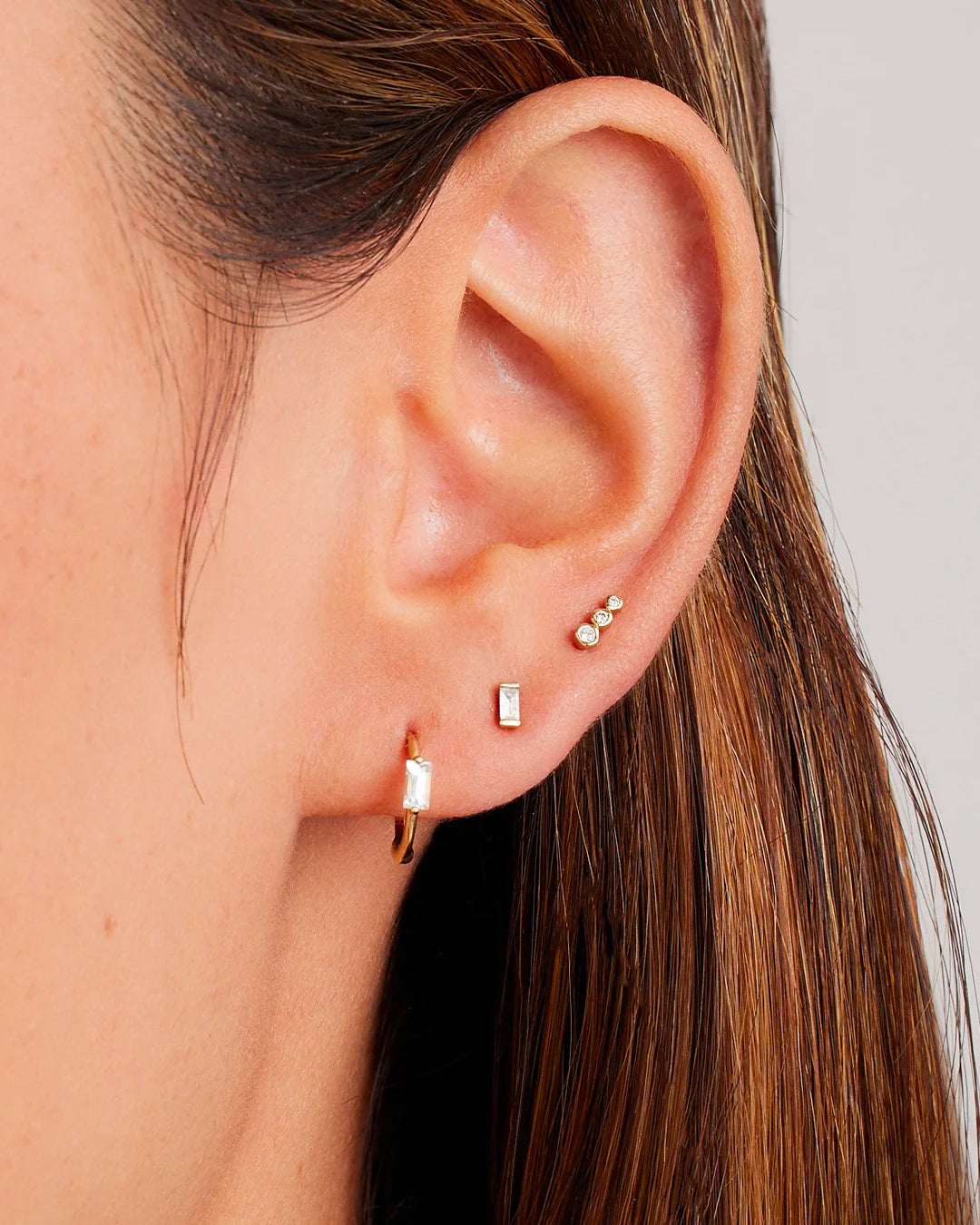 Elegant Solitaire Baguette White Sapphire Huggies featuring sparkling white sapphire stones in a classic huggie design.