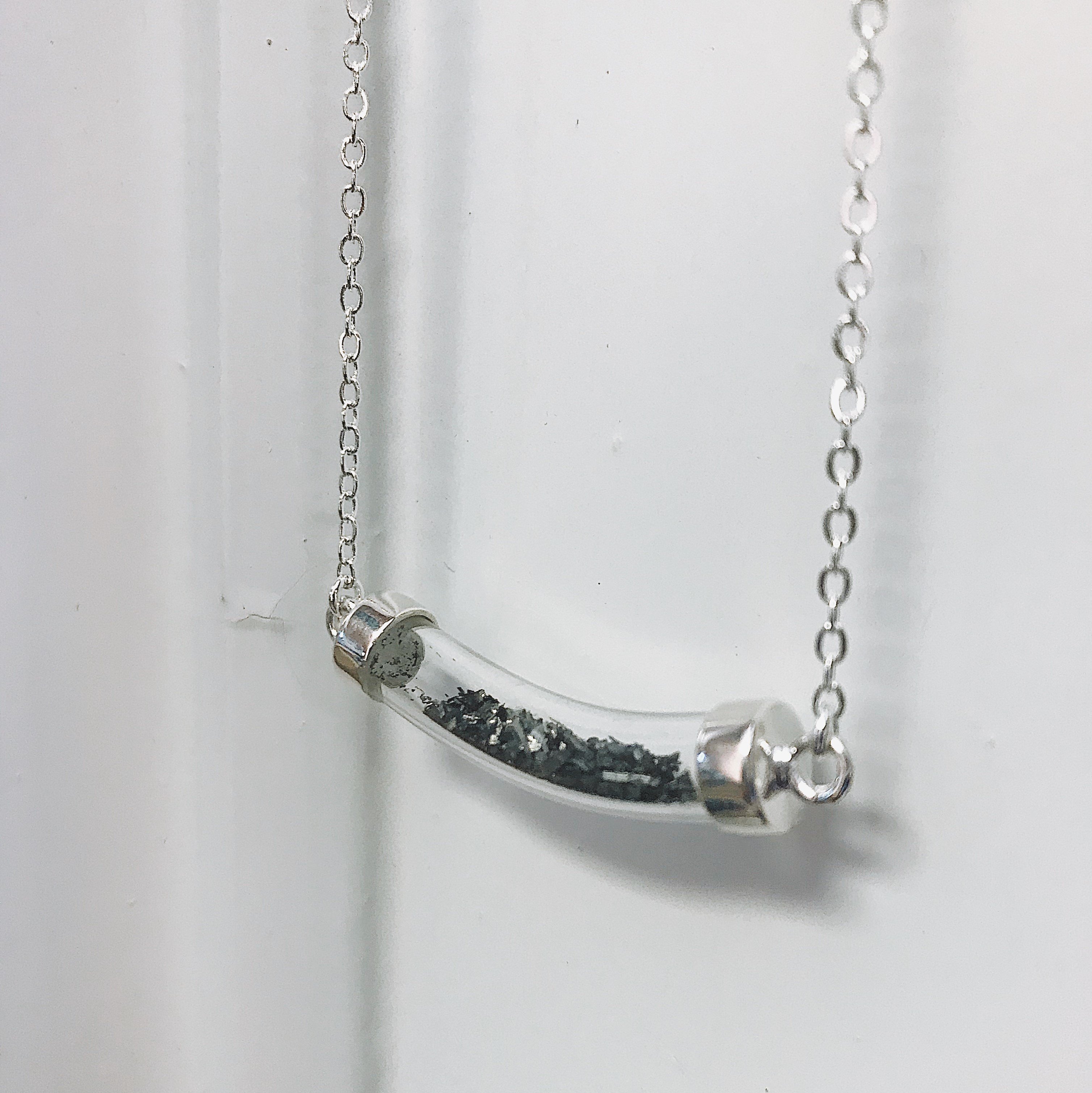 Stardust Vial Specimen Necklace featuring a glass tube filled with genuine meteorite dust, elegantly designed with a rhodium plated brass chain.