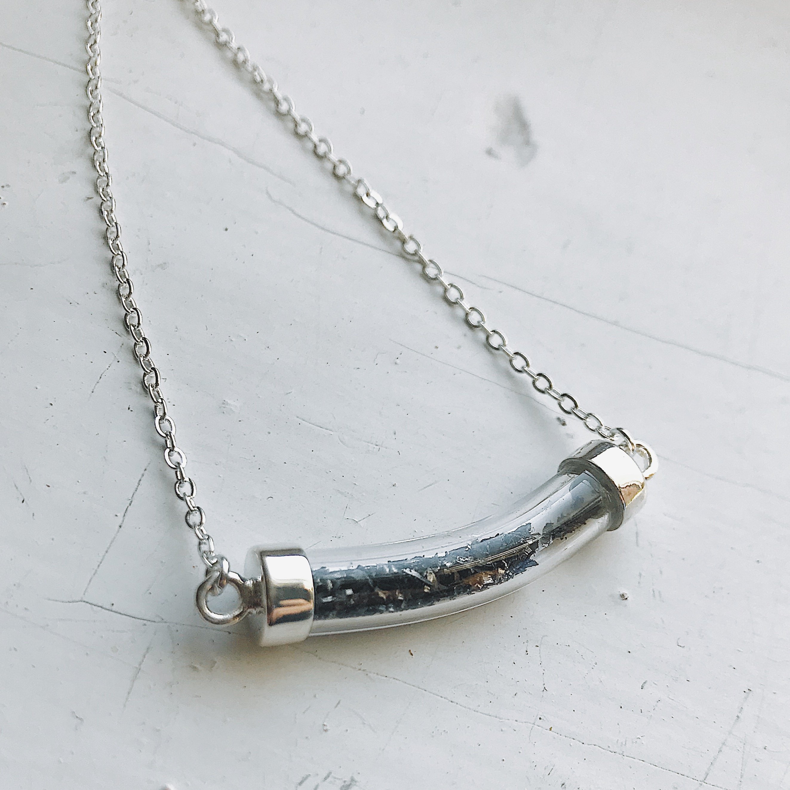 Stardust Vial Specimen Necklace featuring a glass tube filled with genuine meteorite dust, elegantly designed with a rhodium plated brass chain.