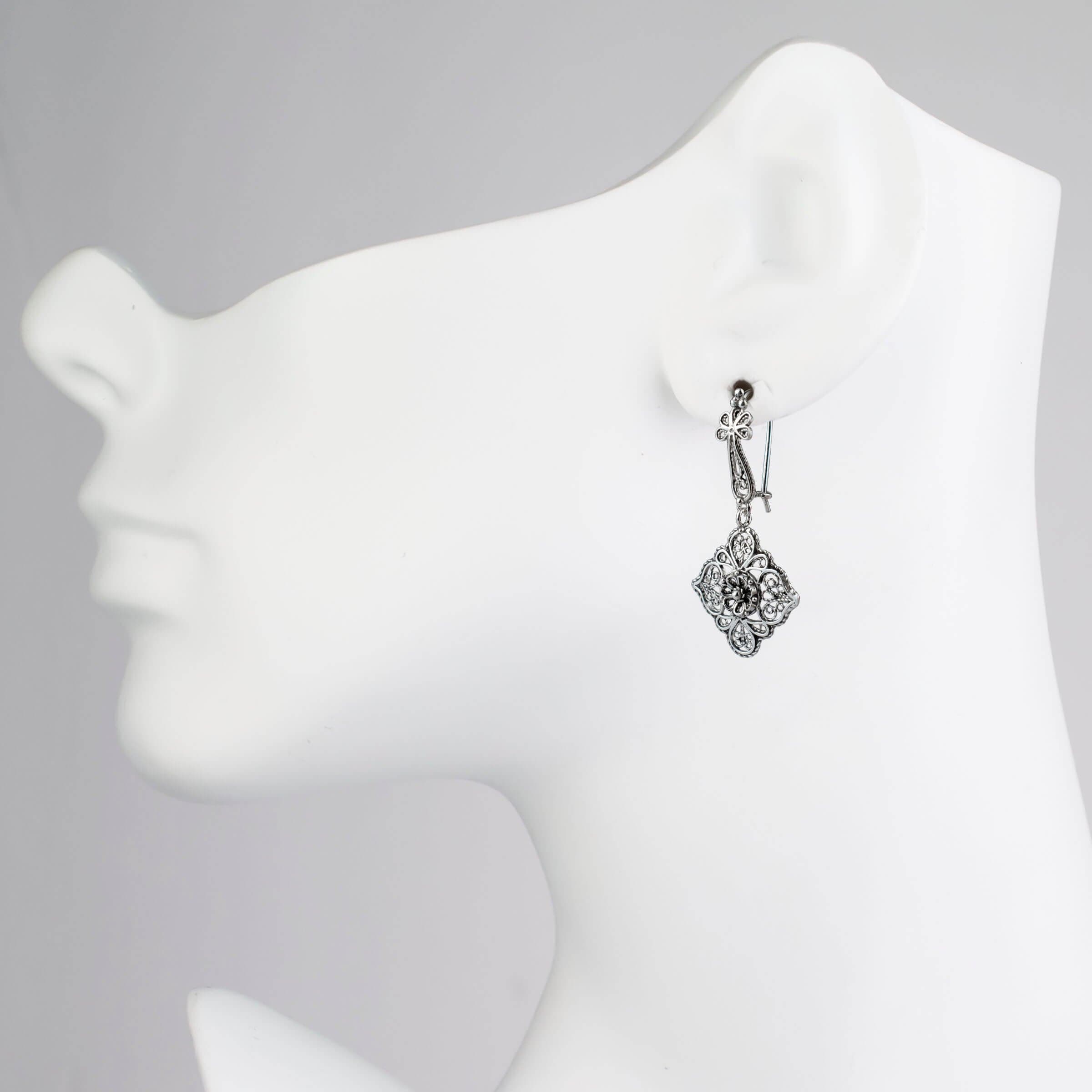 Elegant sterling silver dangle drop earrings featuring intricate filigree flower design, showcasing craftsmanship and sophistication.