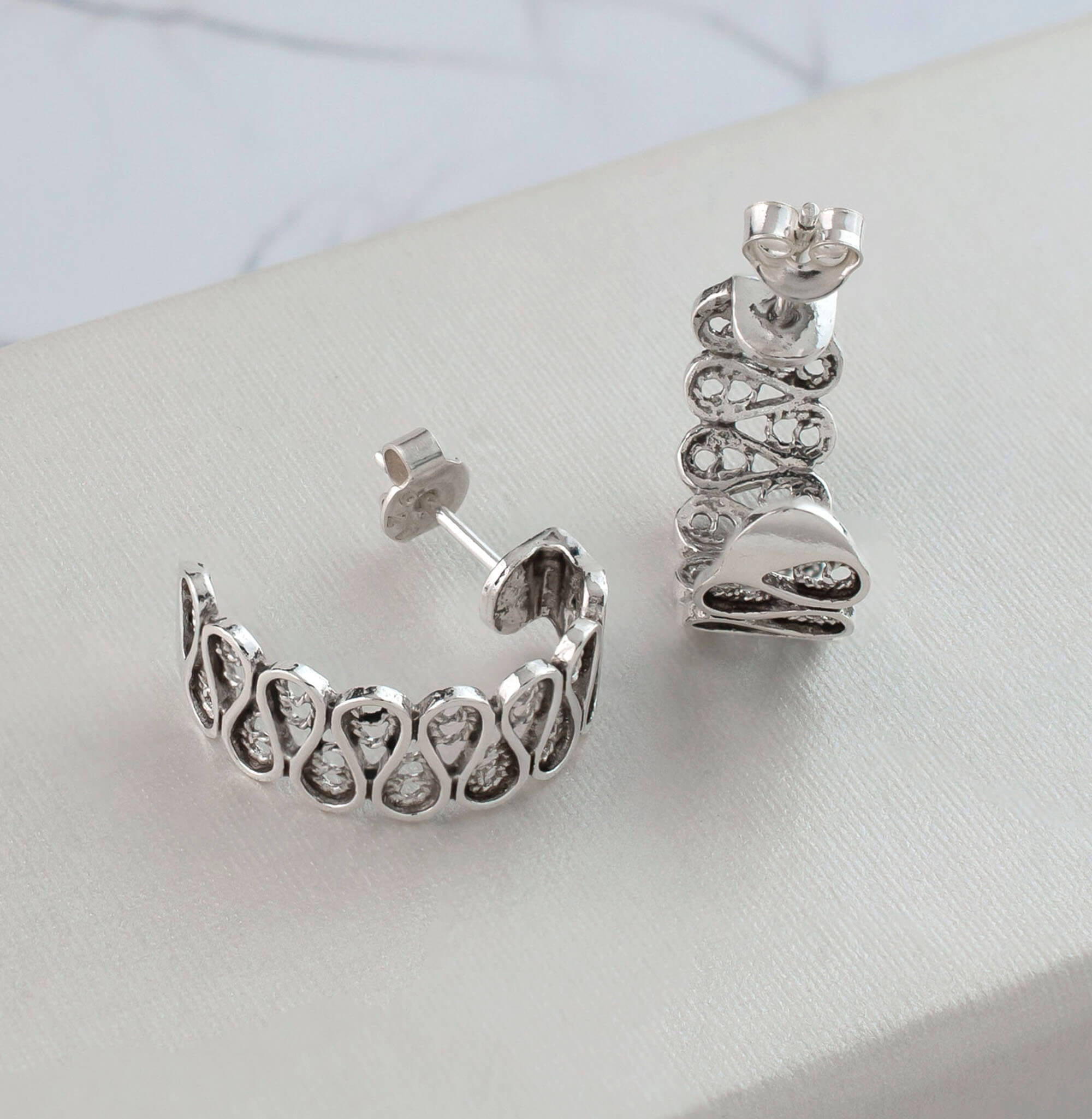 Elegant sterling silver filigree drop earrings with C hoop design, showcasing intricate detailing and polished finish.