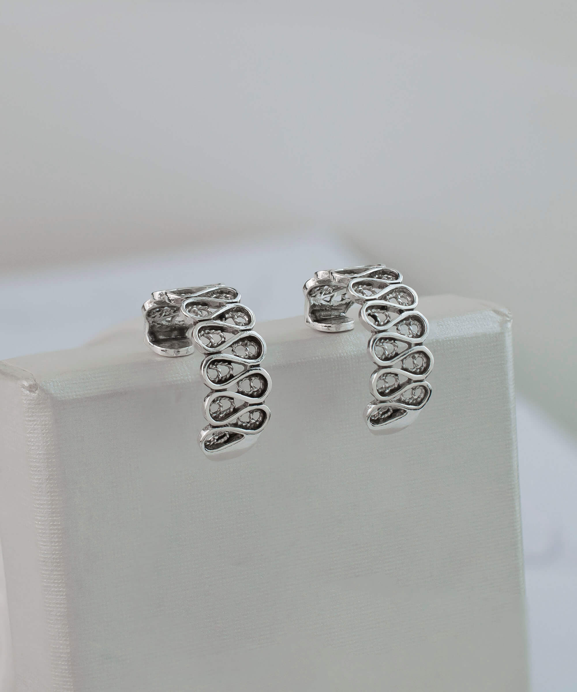 Elegant sterling silver filigree drop earrings with C hoop design, showcasing intricate detailing and polished finish.