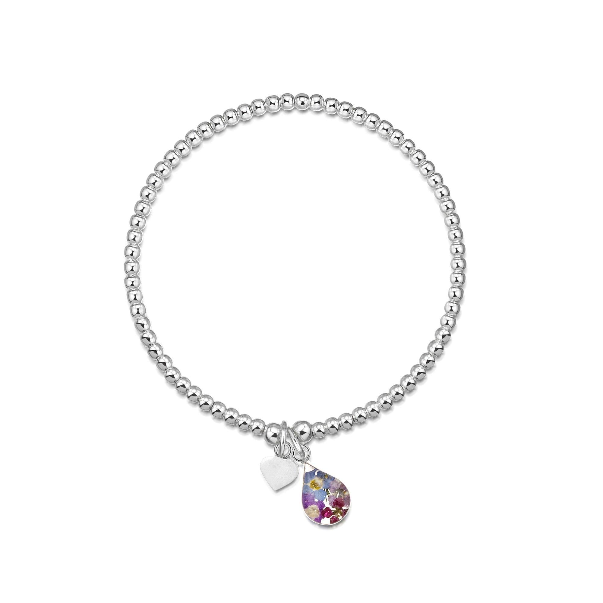Sterling silver stretchy beaded bracelet featuring tiny purple flowers and a heart charm, elegantly displayed in a gift box.