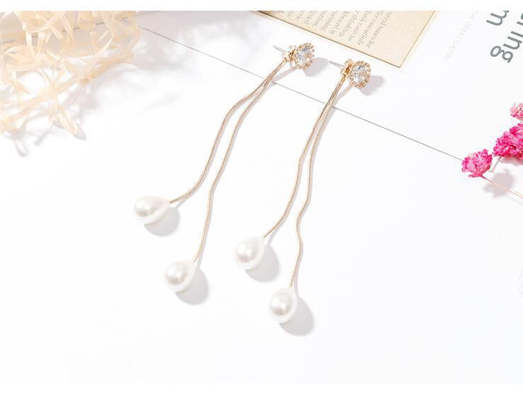 A pair of long tassel earrings featuring rhinestones and pearls, elegantly designed for a stylish look.