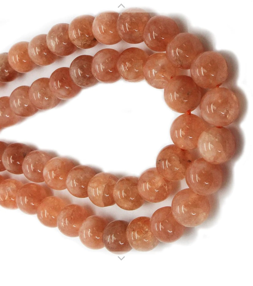A strand of 8 mm SUNSTONE semi-precious gemstone beads, showcasing their natural beauty and shimmering surface.