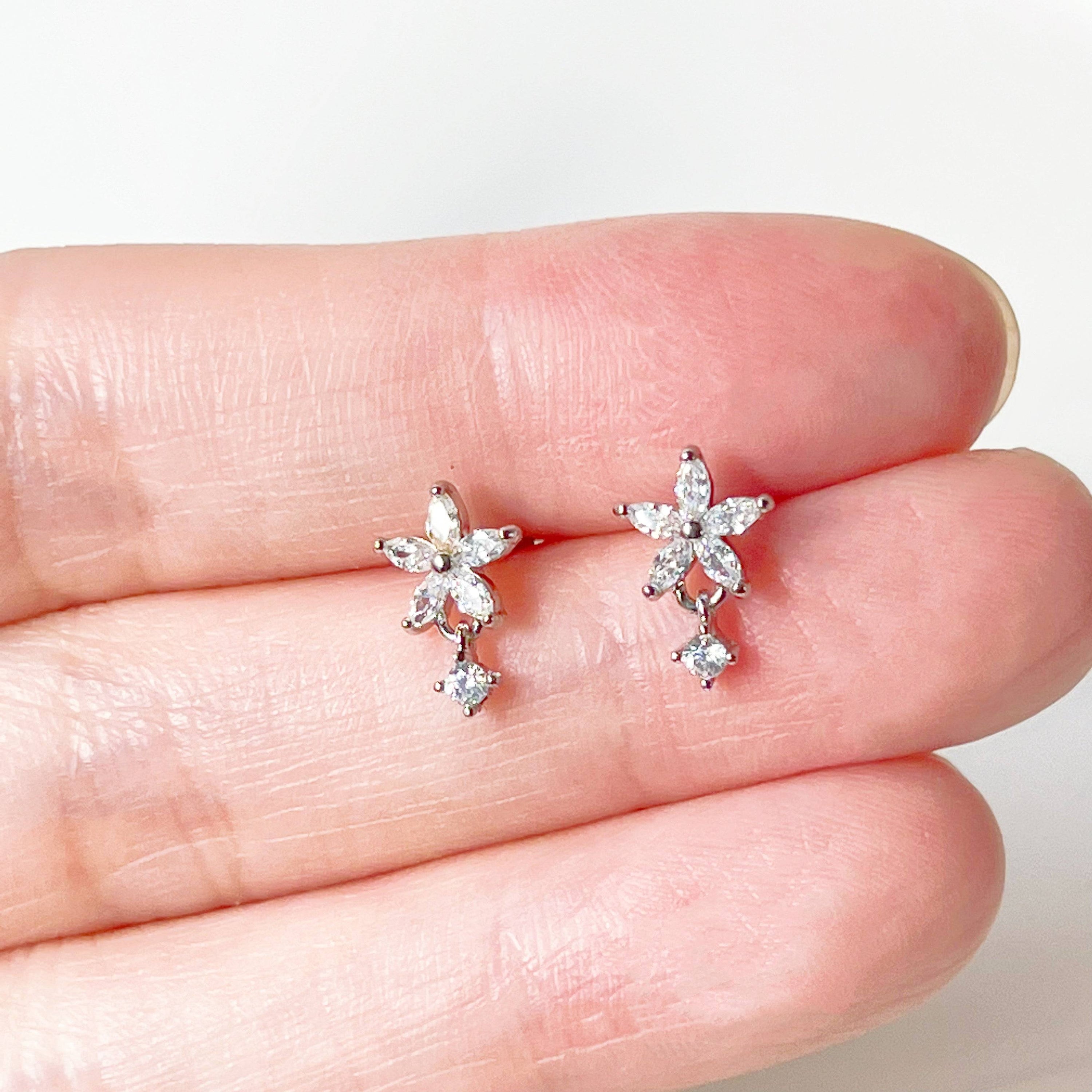 A pair of delicate surgical steel flower earrings featuring clear zircon crystals, elegantly designed for sensitive ears.