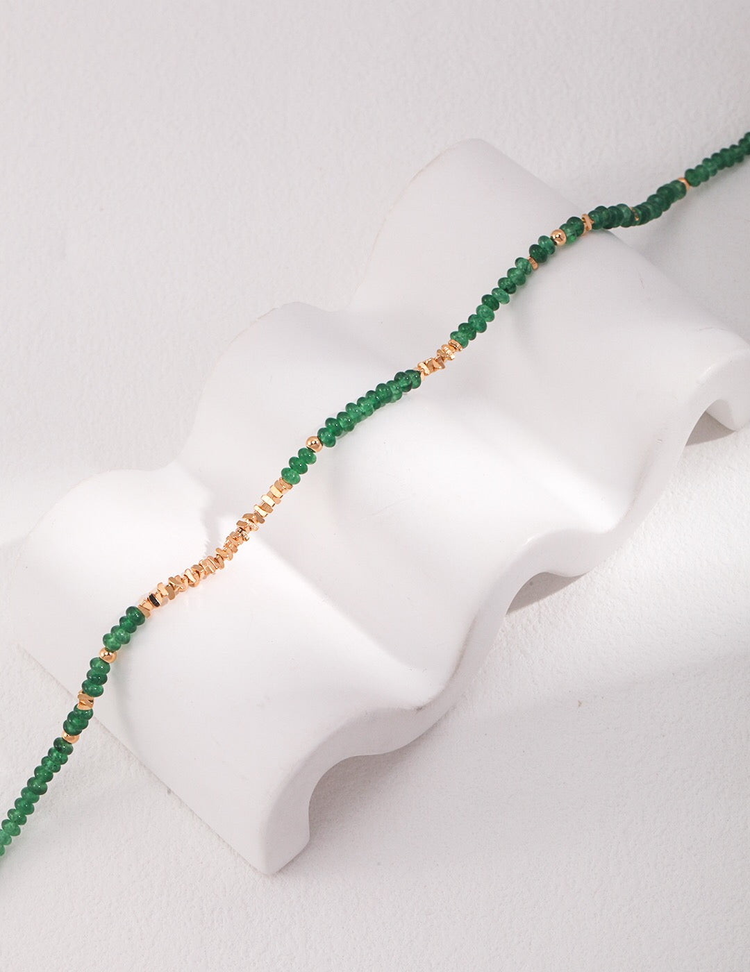 A stunning handmade synthetic emerald beaded necklace with gold vermeil accents, elegantly displayed on a soft background.