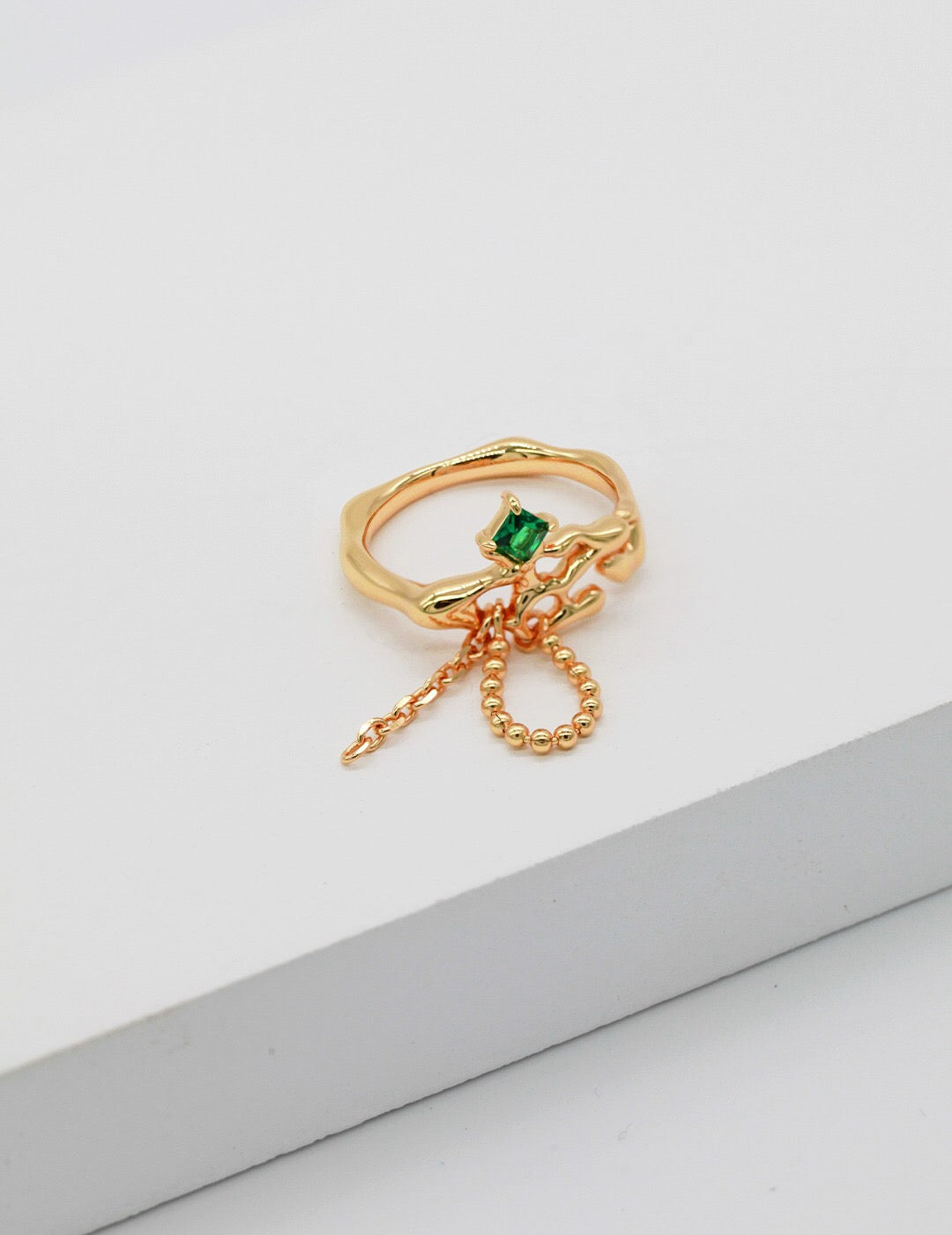 A stunning synthetic green spinel open ring, featuring gold vermeil plating and an adjustable design, elegantly displayed on a soft fabric background.