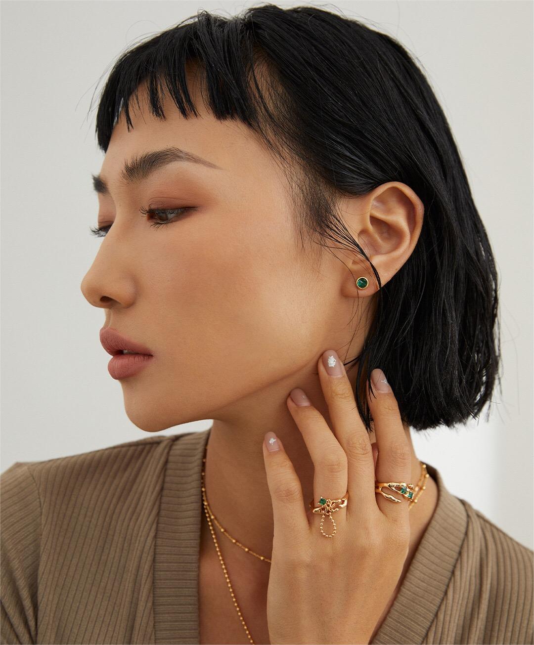 A stunning synthetic green spinel open ring, featuring gold vermeil plating and an adjustable design, elegantly displayed on a soft fabric background.