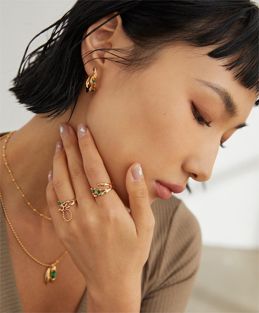 A stunning synthetic green spinel open ring, featuring gold vermeil plating and an adjustable design, elegantly displayed on a soft fabric background.