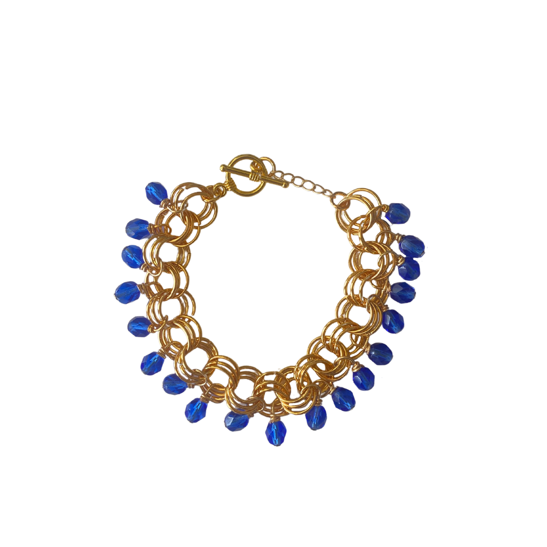 The Donna Bracelet in Light Cobalt Blue featuring Czech glass beads and a toggle clasp, handcrafted with gold/silver-plated brass links.