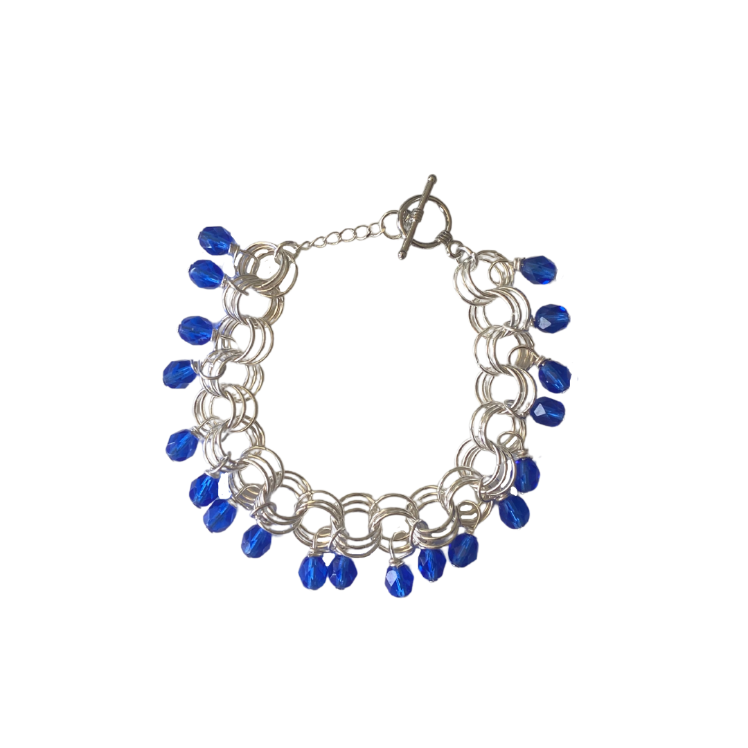 The Donna Bracelet in Light Cobalt Blue featuring Czech glass beads and a toggle clasp, handcrafted with gold/silver-plated brass links.