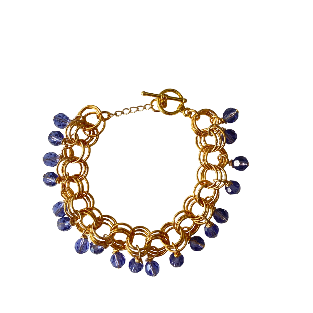 The Donna Bracelet in Tanzanite featuring gold/silver-plated links and tanzanite Czech fire-polished glass beads with a toggle clasp.