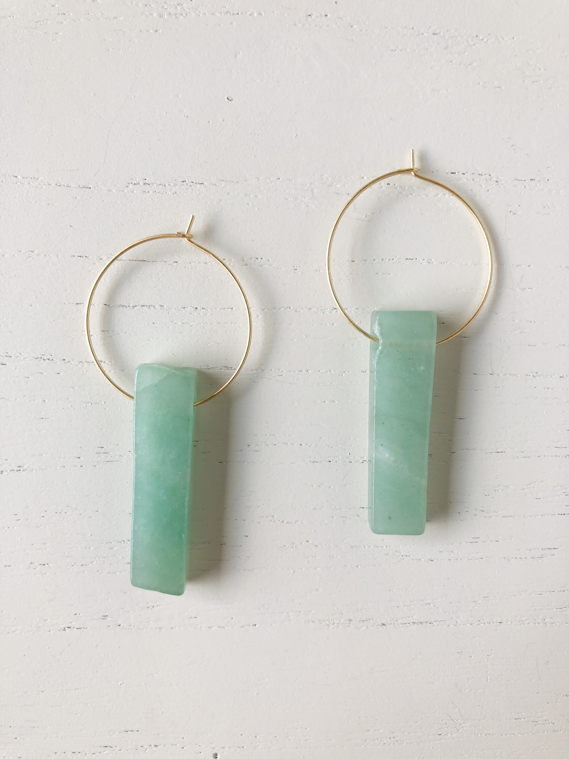 The Henley Aventurine earrings featuring a brass hoop and genuine aventurine stone, showcasing their unique design and vibrant color.