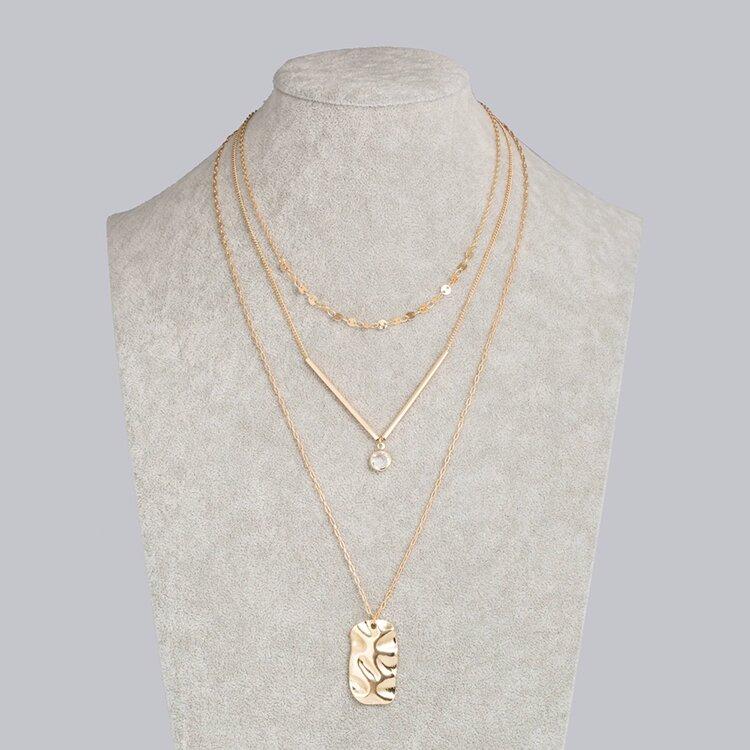 Three layer necklace featuring a gold bar and cubic zirconia pendant, elegantly designed for stylish layering.