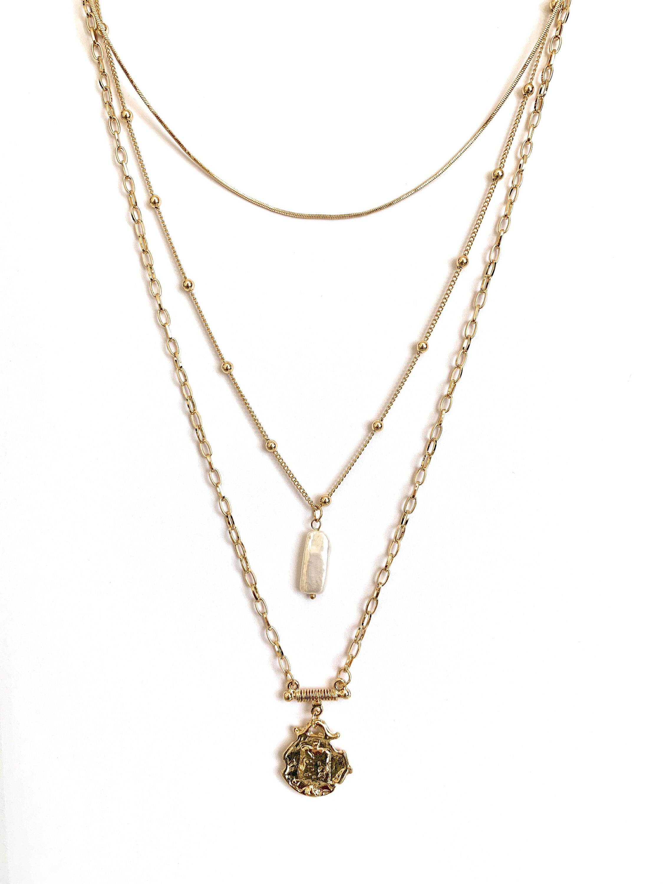 Three layer necklace featuring simulated pearl and gold pendant, elegantly designed with textured links and beaded accents.
