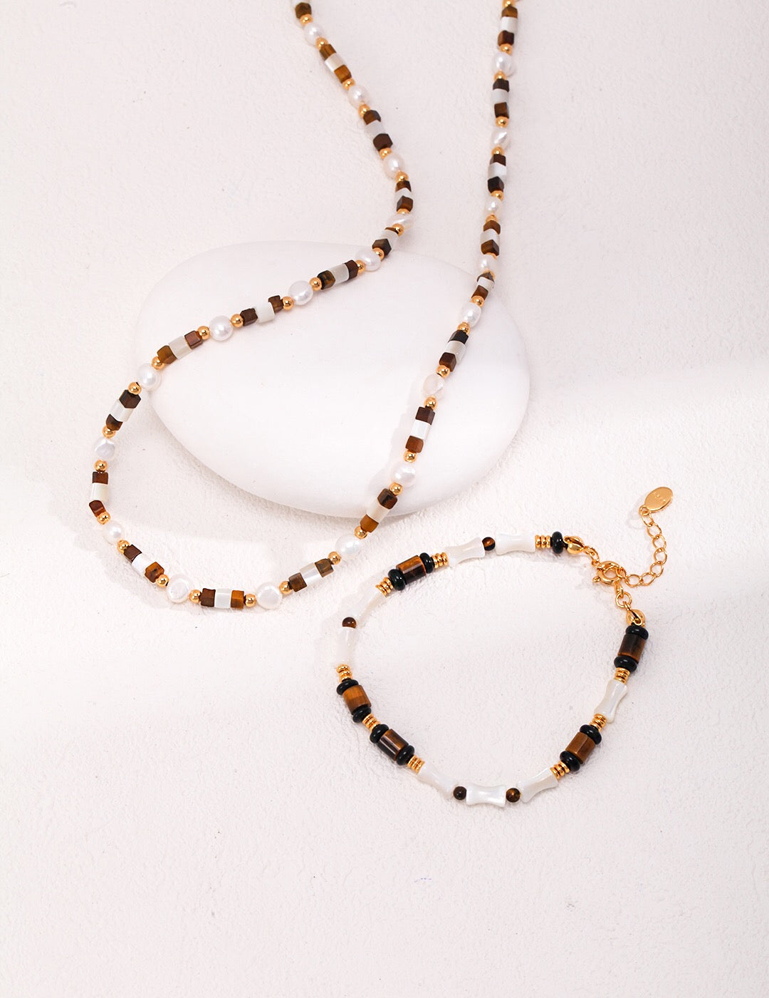 A beautifully handcrafted bracelet featuring tiger eye stones, mother shell, and black agate, with a gold vermeil chain.