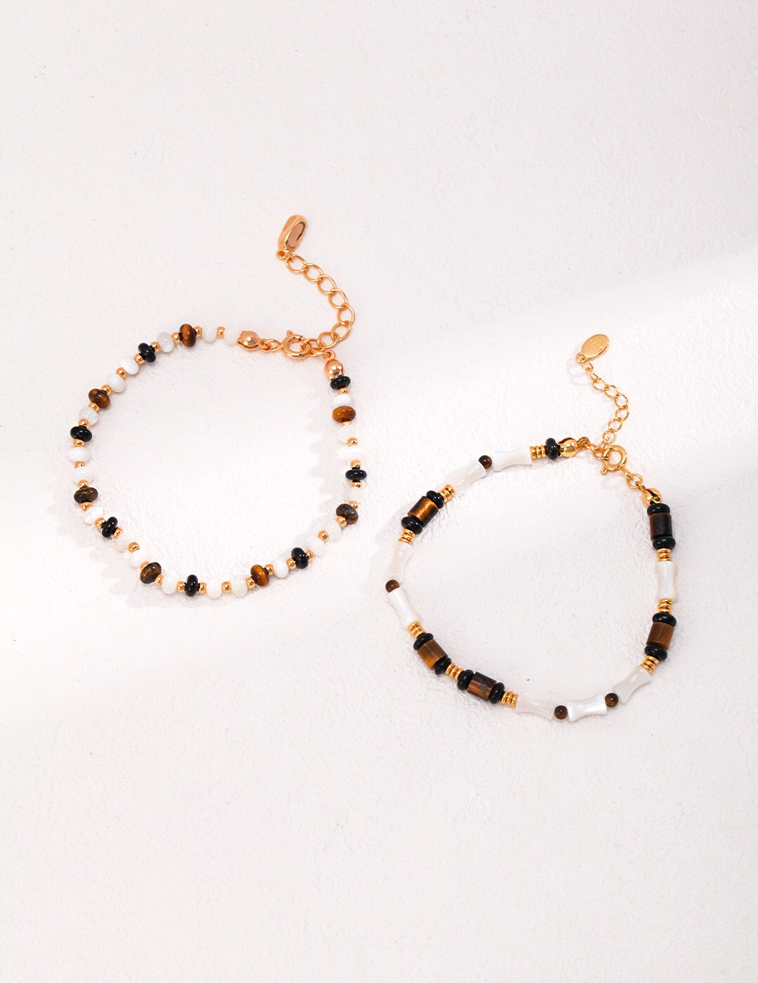 A beautifully handcrafted bracelet featuring tiger eye stones, mother shell, and black agate, with a gold vermeil chain.