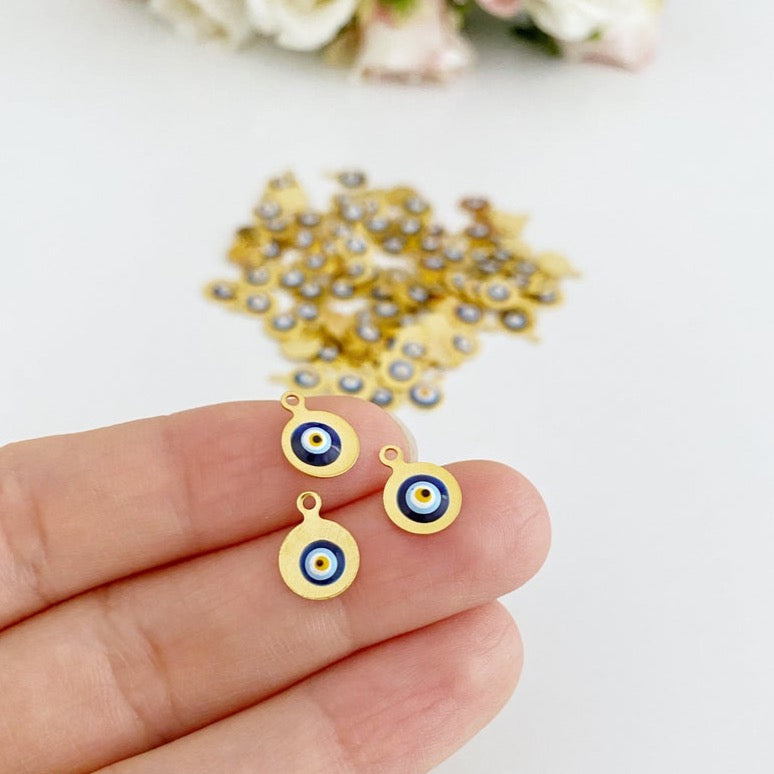 Tiny gold evil eye bead charm on a white background, showcasing its 10mm size and intricate design.