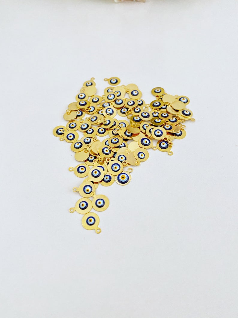 Tiny gold evil eye bead charm on a white background, showcasing its 10mm size and intricate design.