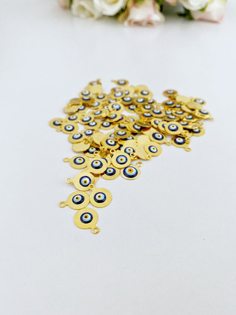 Tiny gold evil eye bead charm on a white background, showcasing its 10mm size and intricate design.