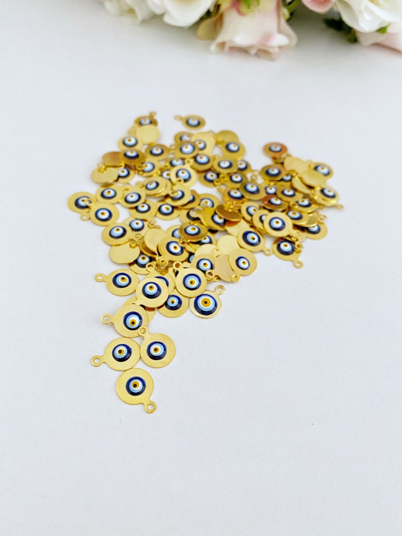 Tiny gold evil eye bead charm on a white background, showcasing its 10mm size and intricate design.